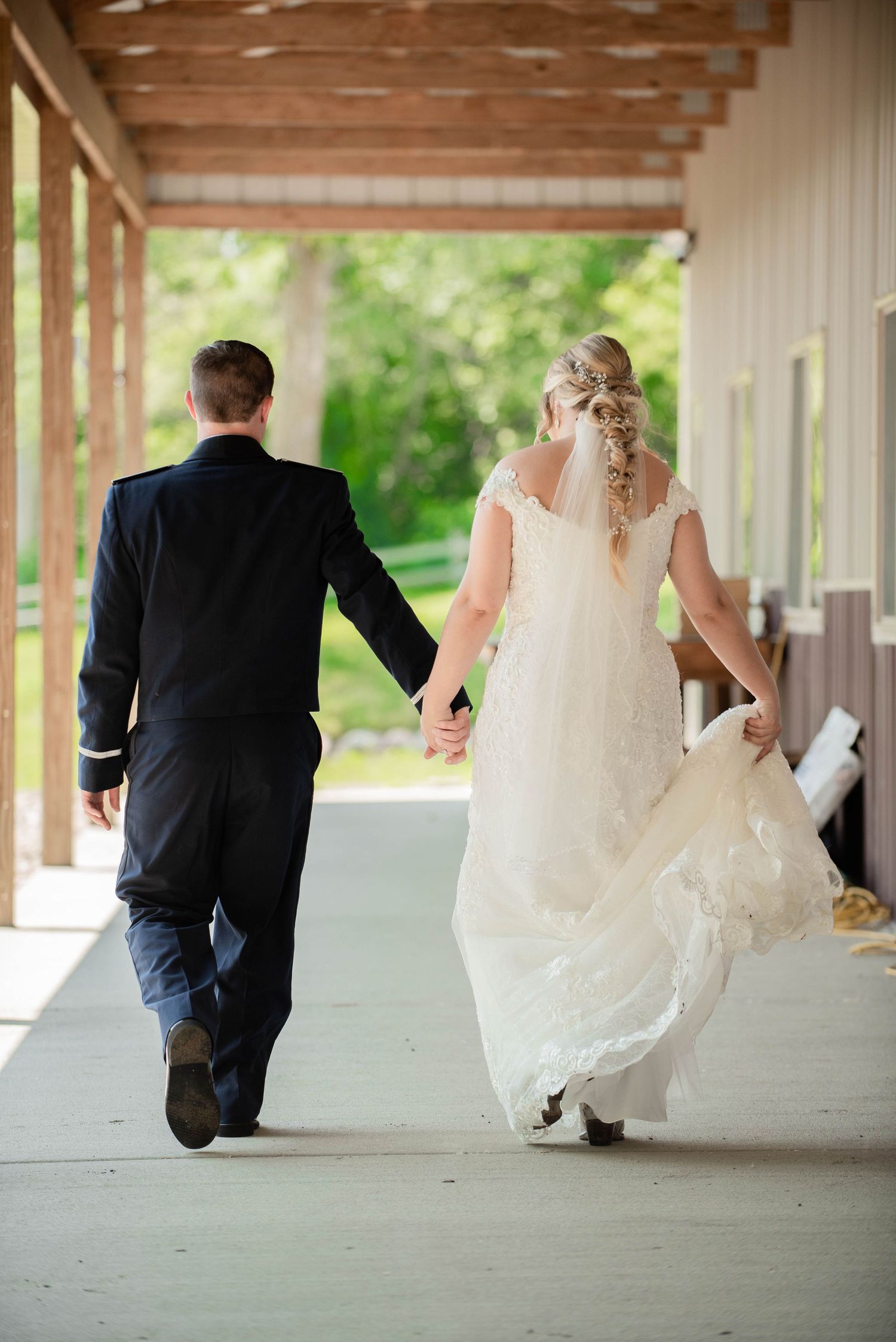 A couple walking down a covered walkway after their wedding ceremony, shown from behind. Zimmerman MN Weddings