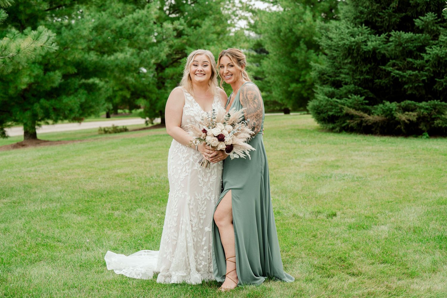 Wedding party members share joyful laughs together on green lawn during outdoor photo session.