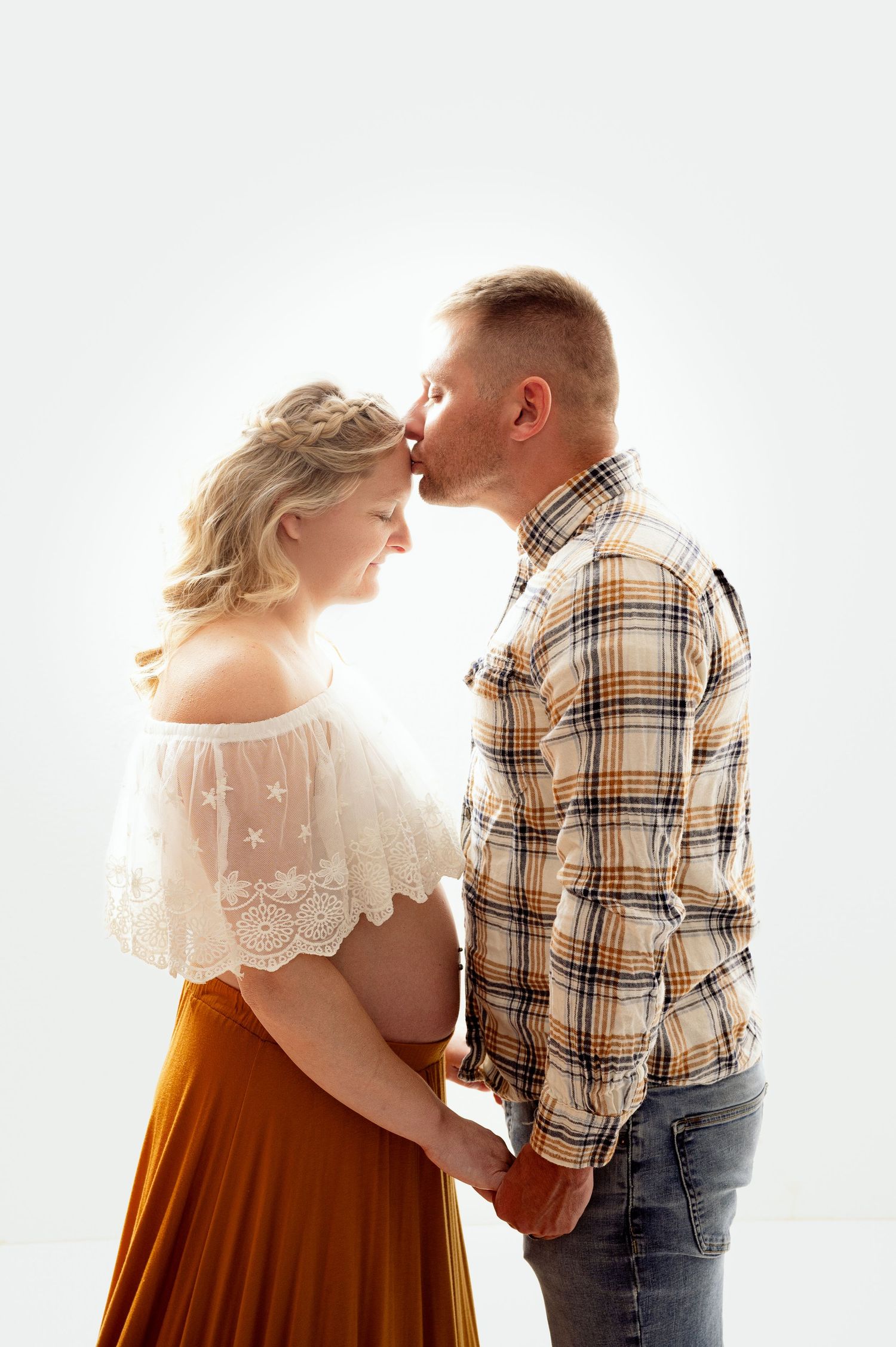 Romantic couple portraits showing tender moments in plaid shirt and lace dress against white backdrop.