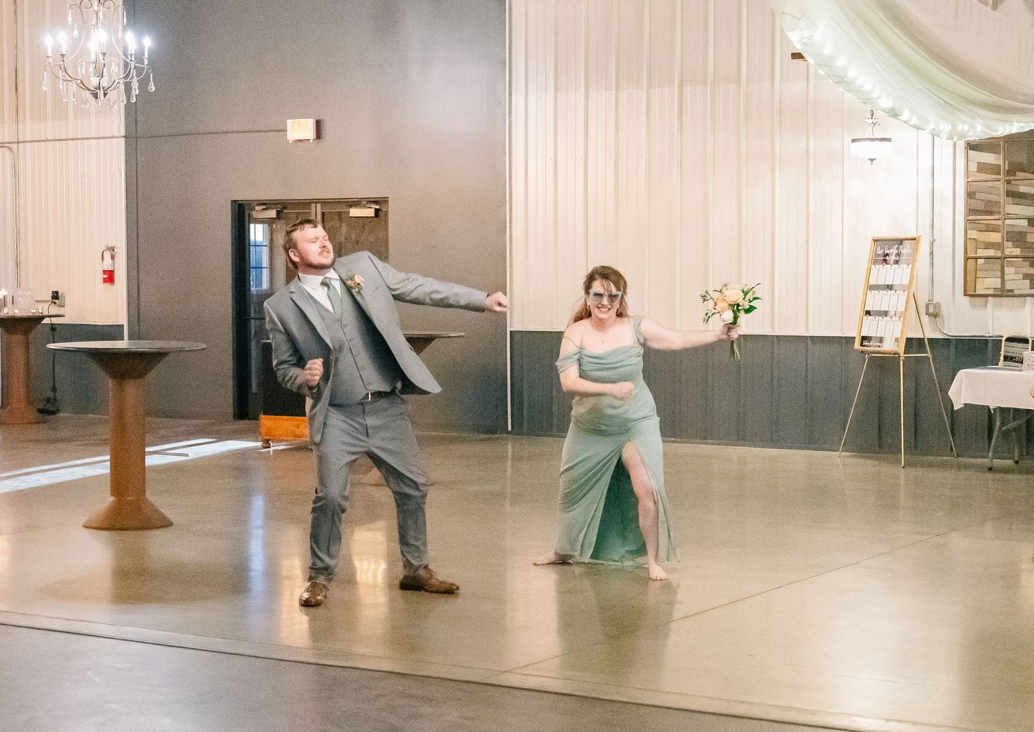 Man and woman in formal attire performing fun dance routine at wedding reception.