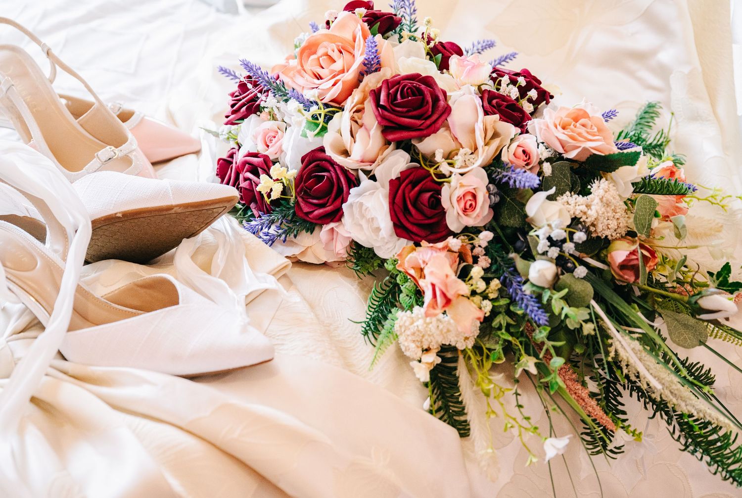 Wedding at The Historic Concord Exchange Minneapolis MN. Elegant bridal bouquet with red and pink roses beside white heels on a white dress.