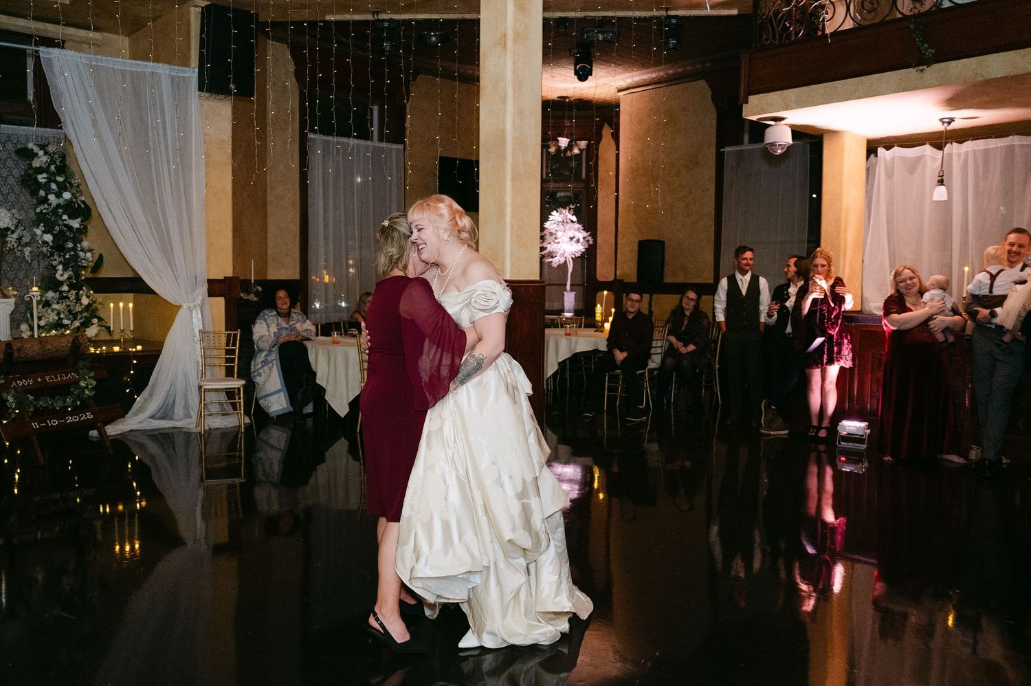 Central MN Wedding Photos | Groom in burgundy suit lifting bride in golden ballgown during first dance at reception.