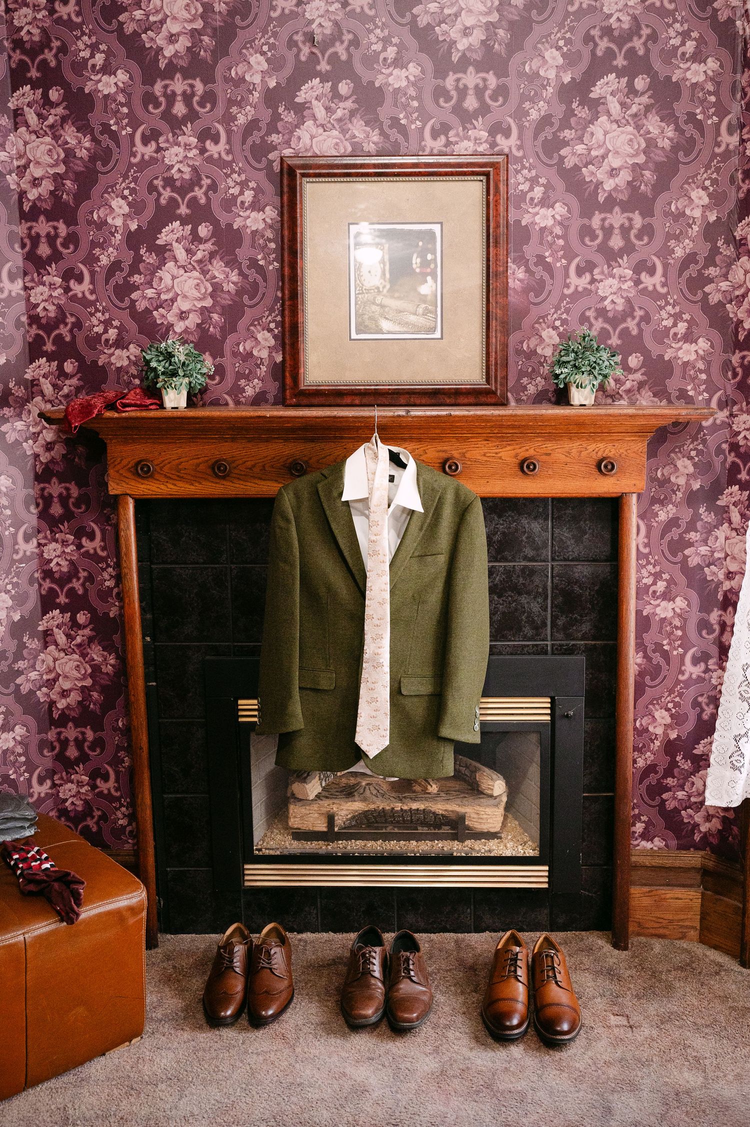 Central MN Wedding Photos | Green suit jacket with tie displayed on fireplace mantel with brown dress shoes arranged below on carpet.