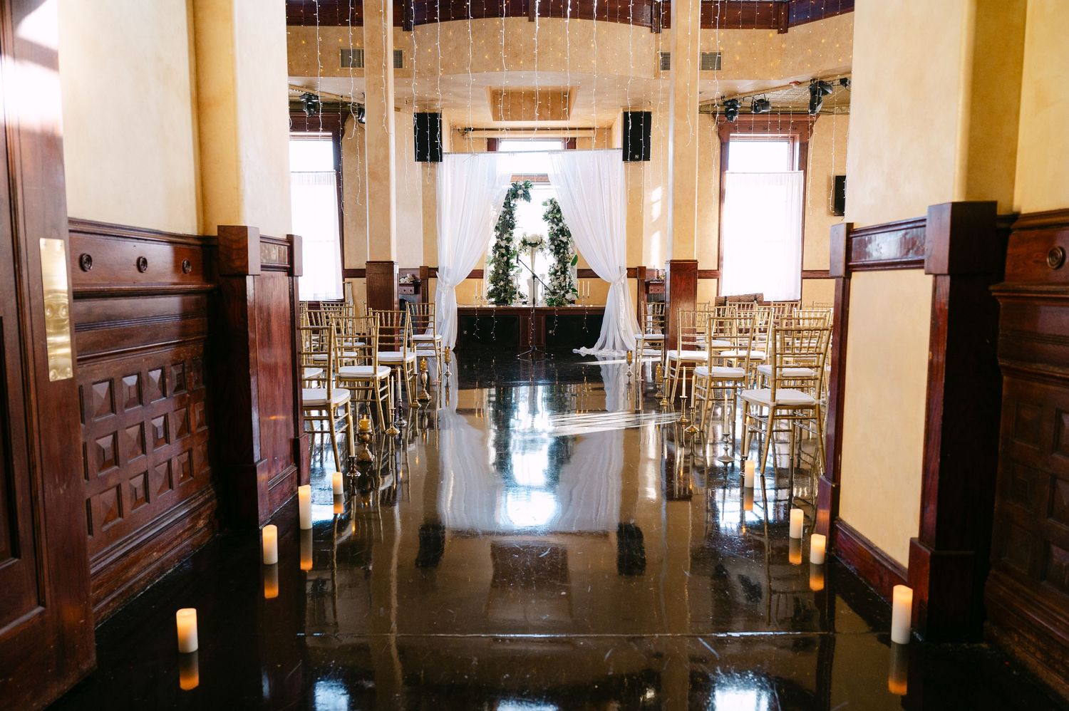 Central MN Wedding Photos | Elegant wedding ceremony aisle with candles, gold chairs, and floral altar decor.