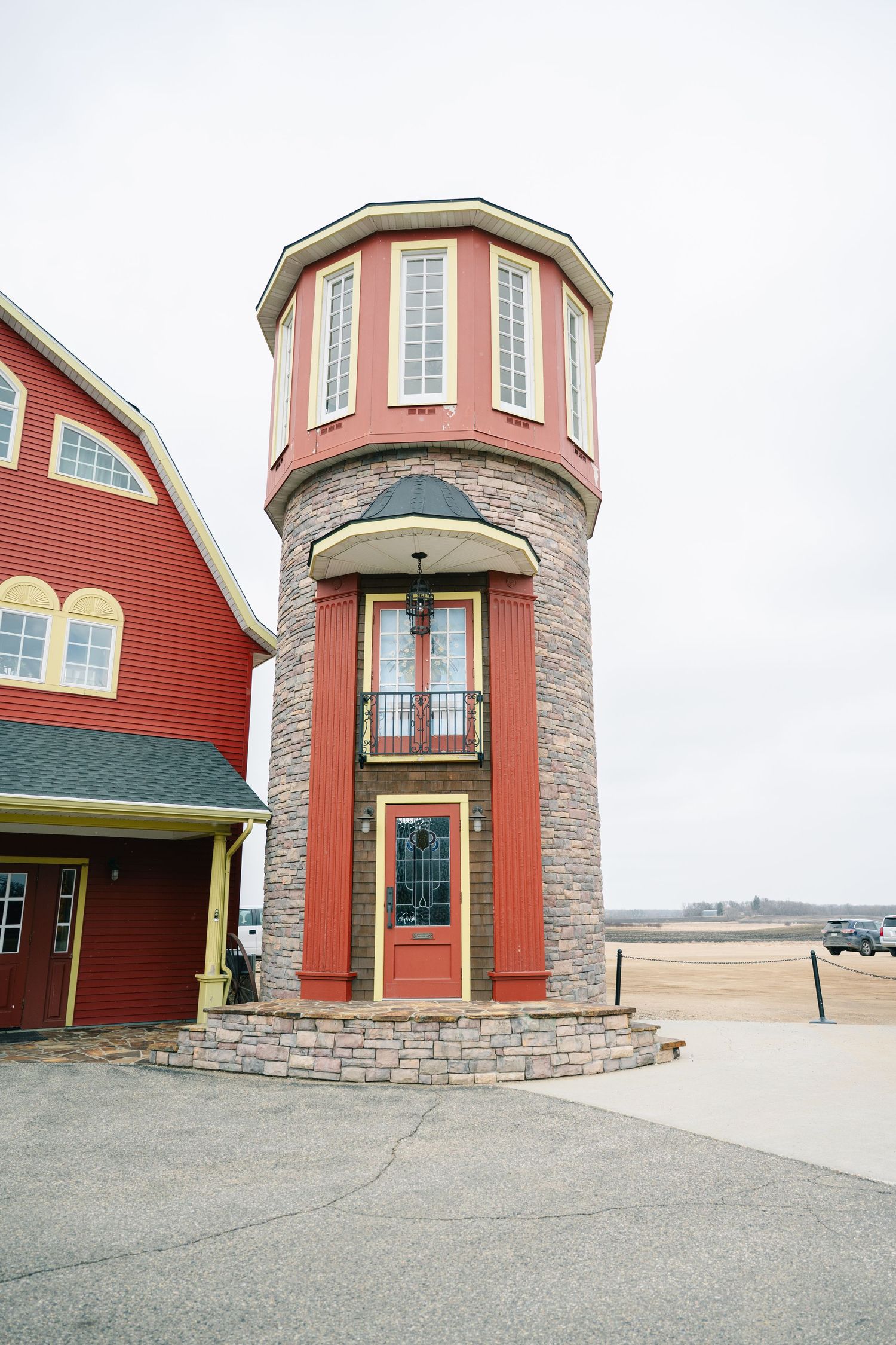 Red and stone cylindrical tower entrance of a rustic wedding venue on an overcast day.