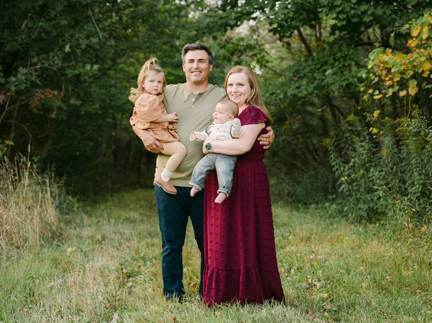 Family of four posing together outdoors in a natural setting during golden hour photography session.. Minnesota milestone photographer