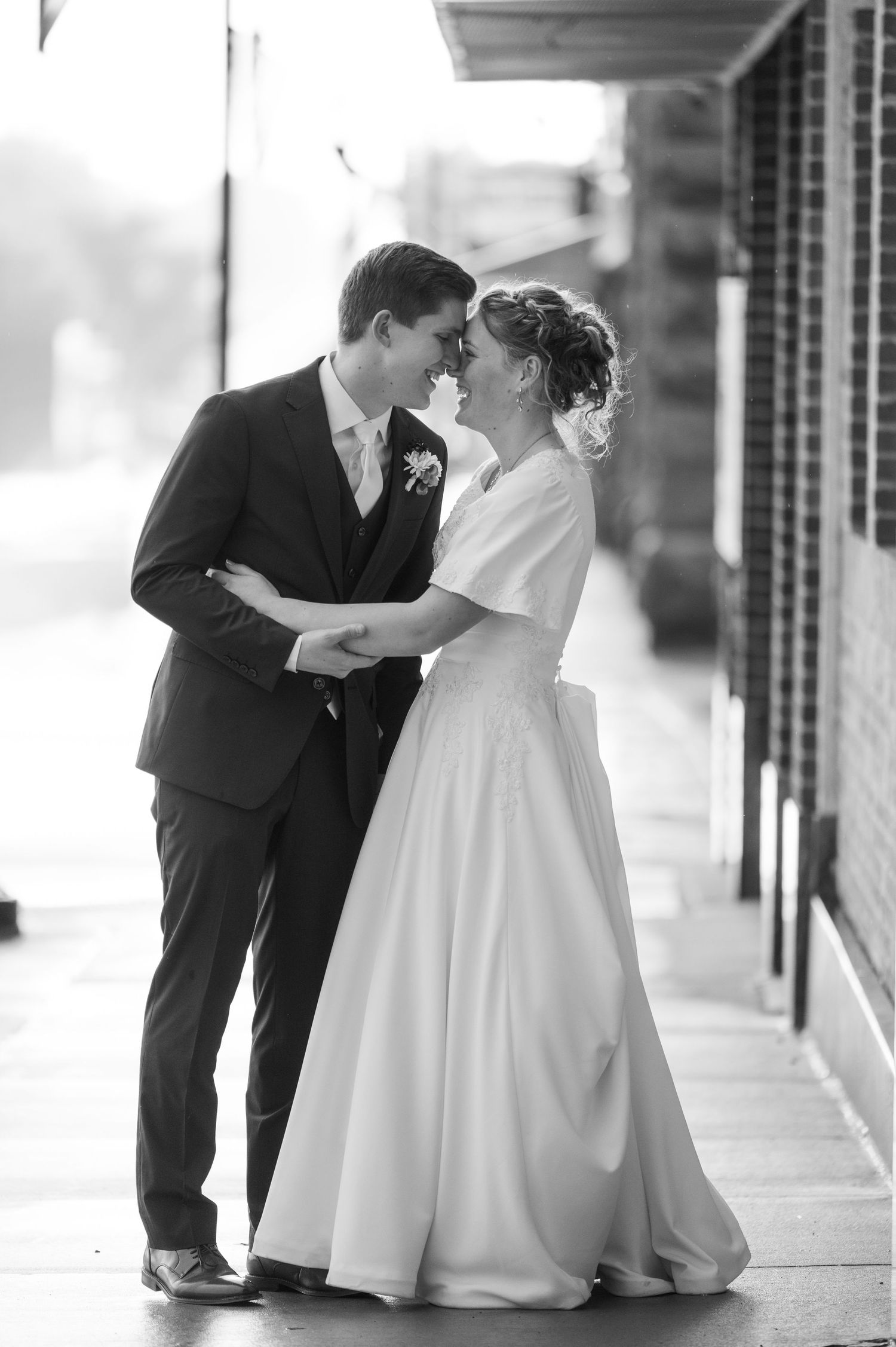 A romantic moment captured in black and white on a covered walkway.