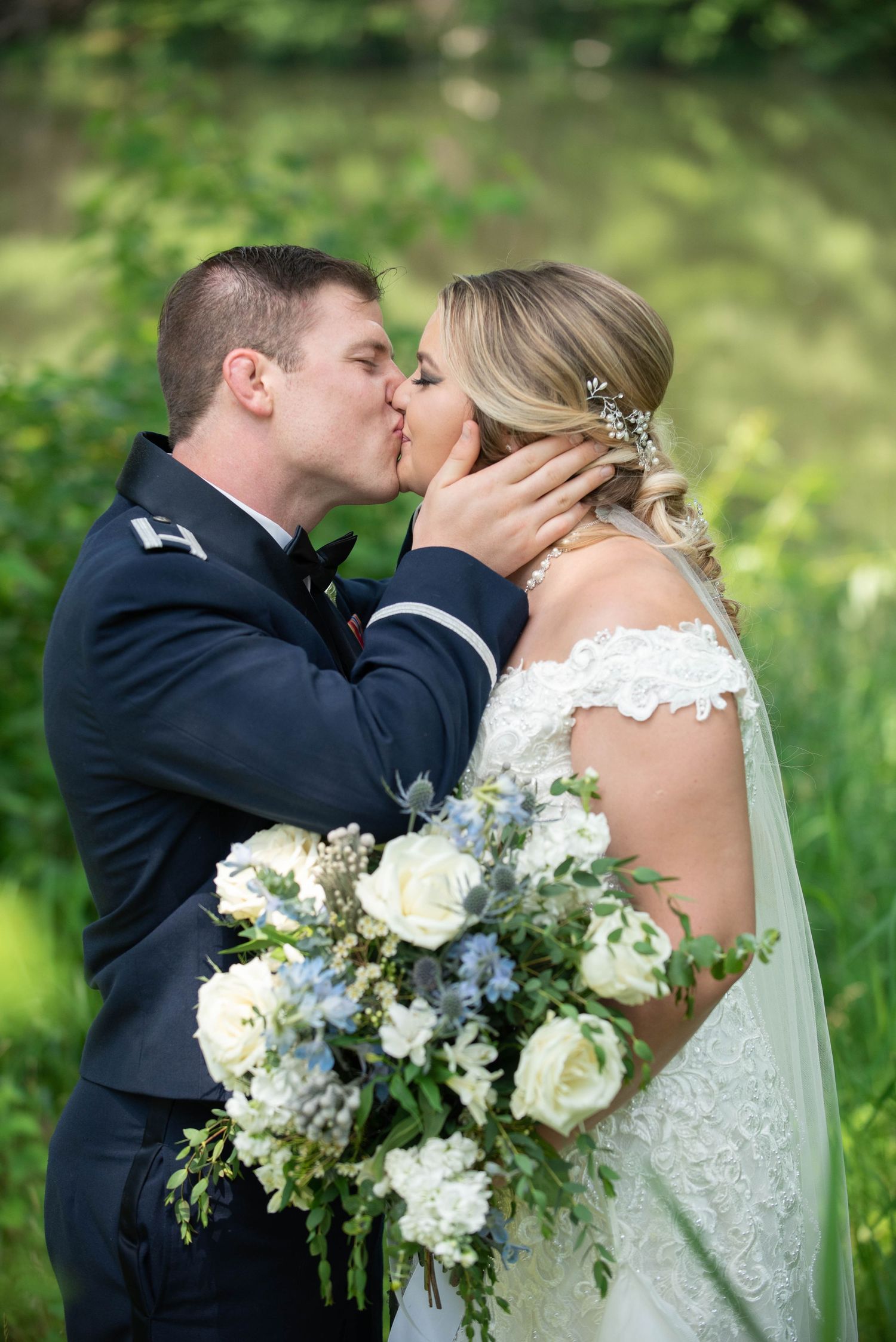 A romantic kiss between newlyweds with a beautiful white floral bouquet. Zimmerman MN Weddings