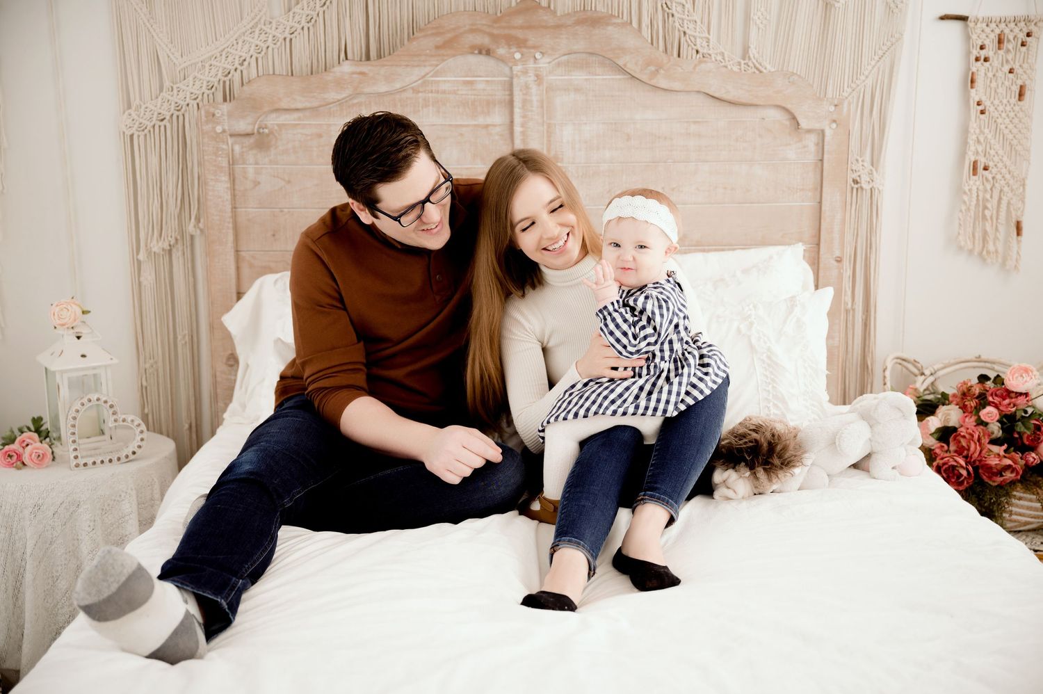 Casual family photo session on white bedding with rustic decor.