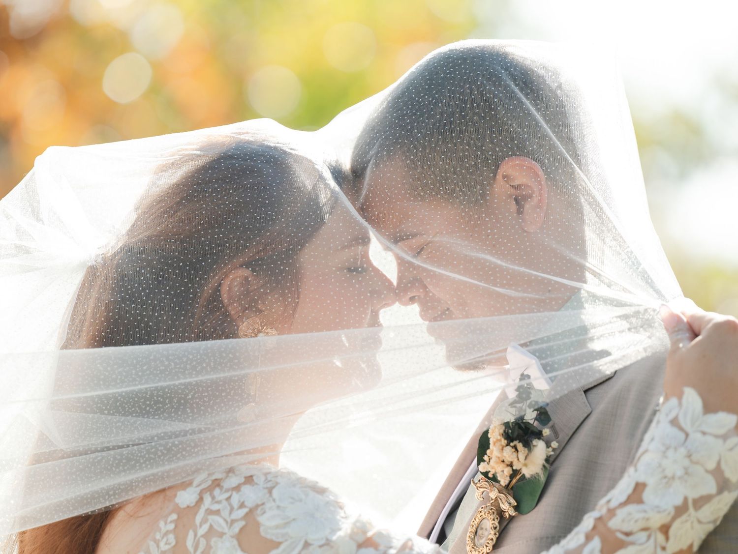 Elegant wedding party poses outdoors on sunny autumn day with white dresses and flowing veils.