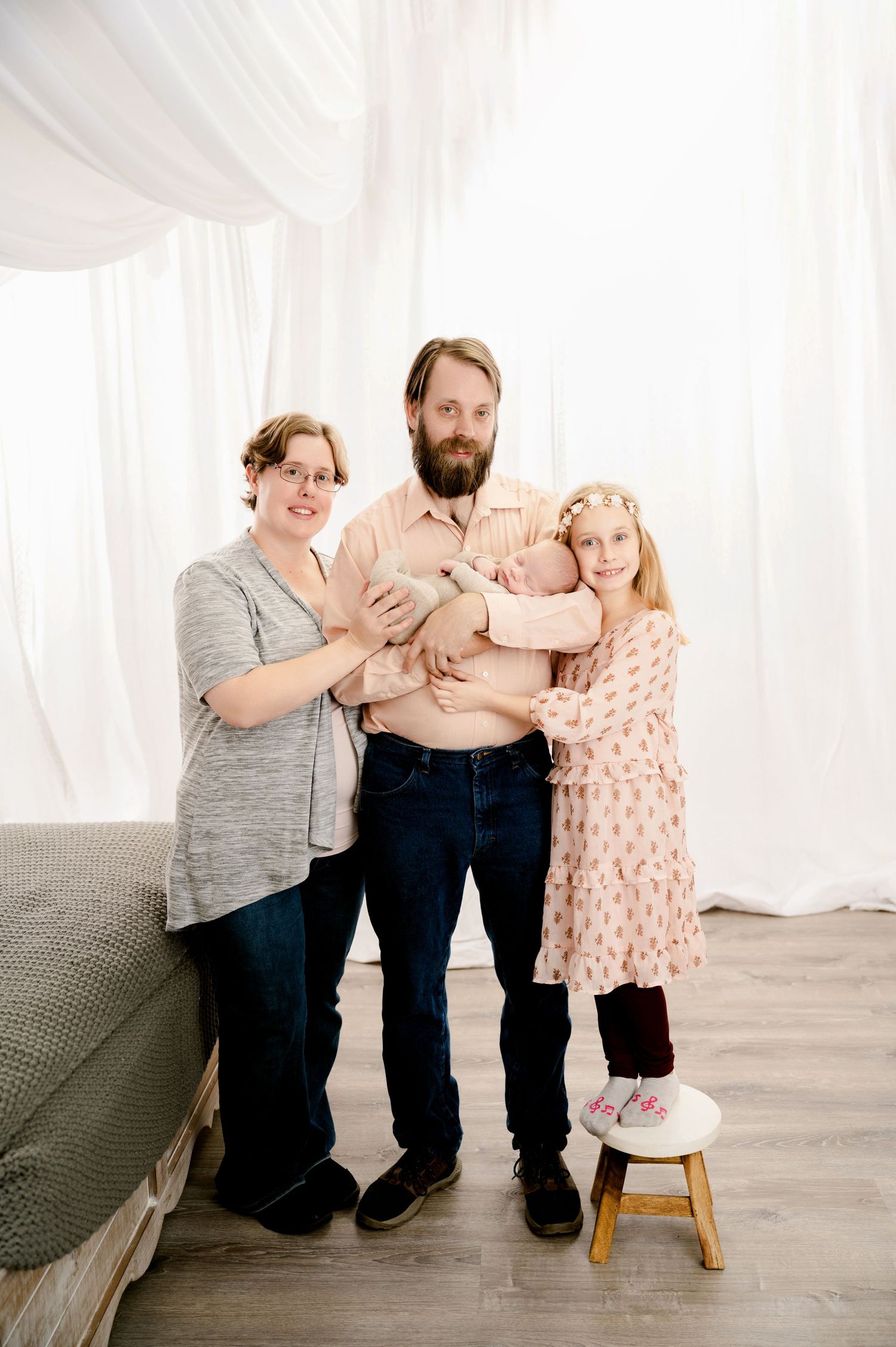 A family in casual clothing shares loving moments in a bright white studio setting.
