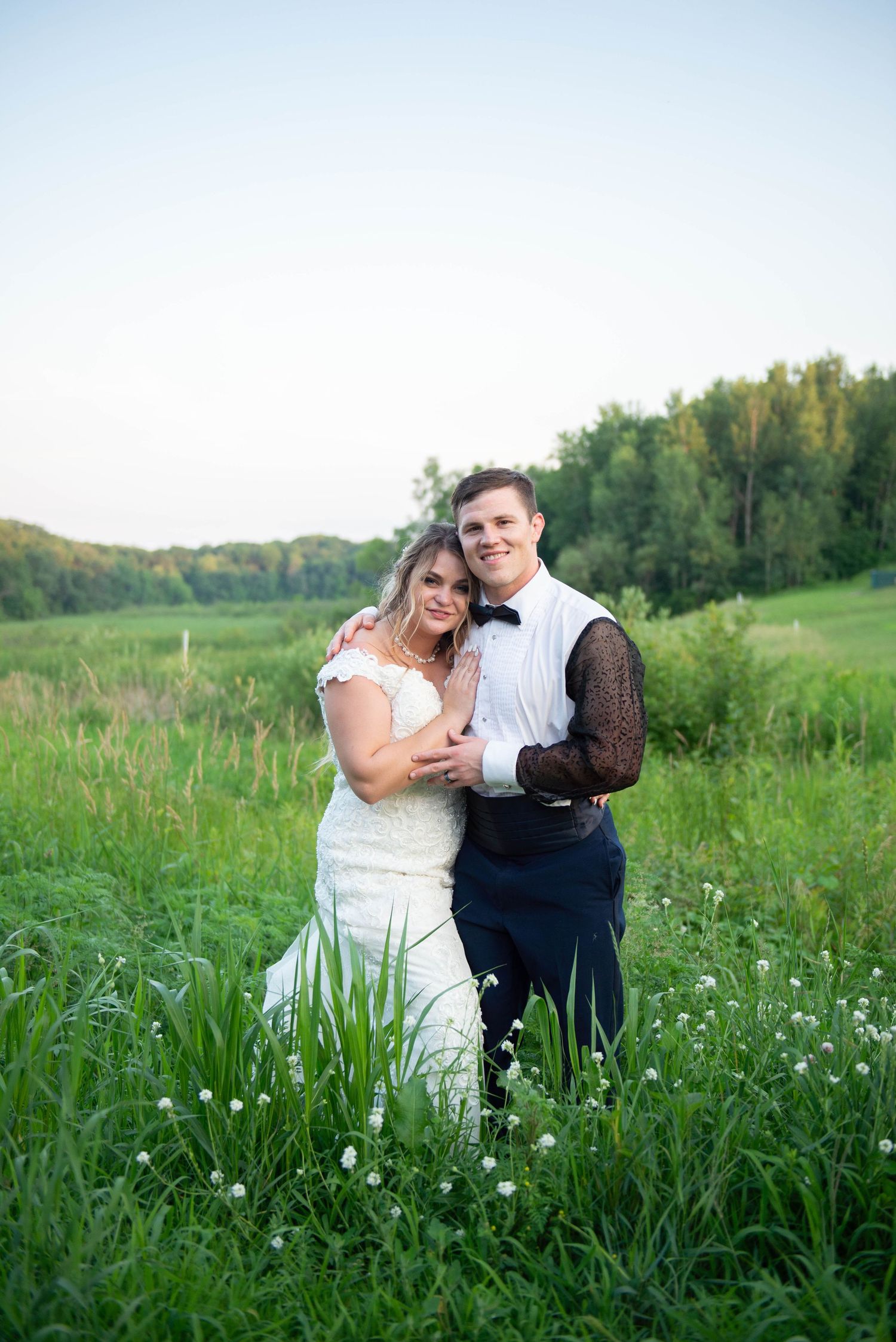 Newlyweds embrace in a scenic meadow at golden hour. Zimmerman MN Weddings