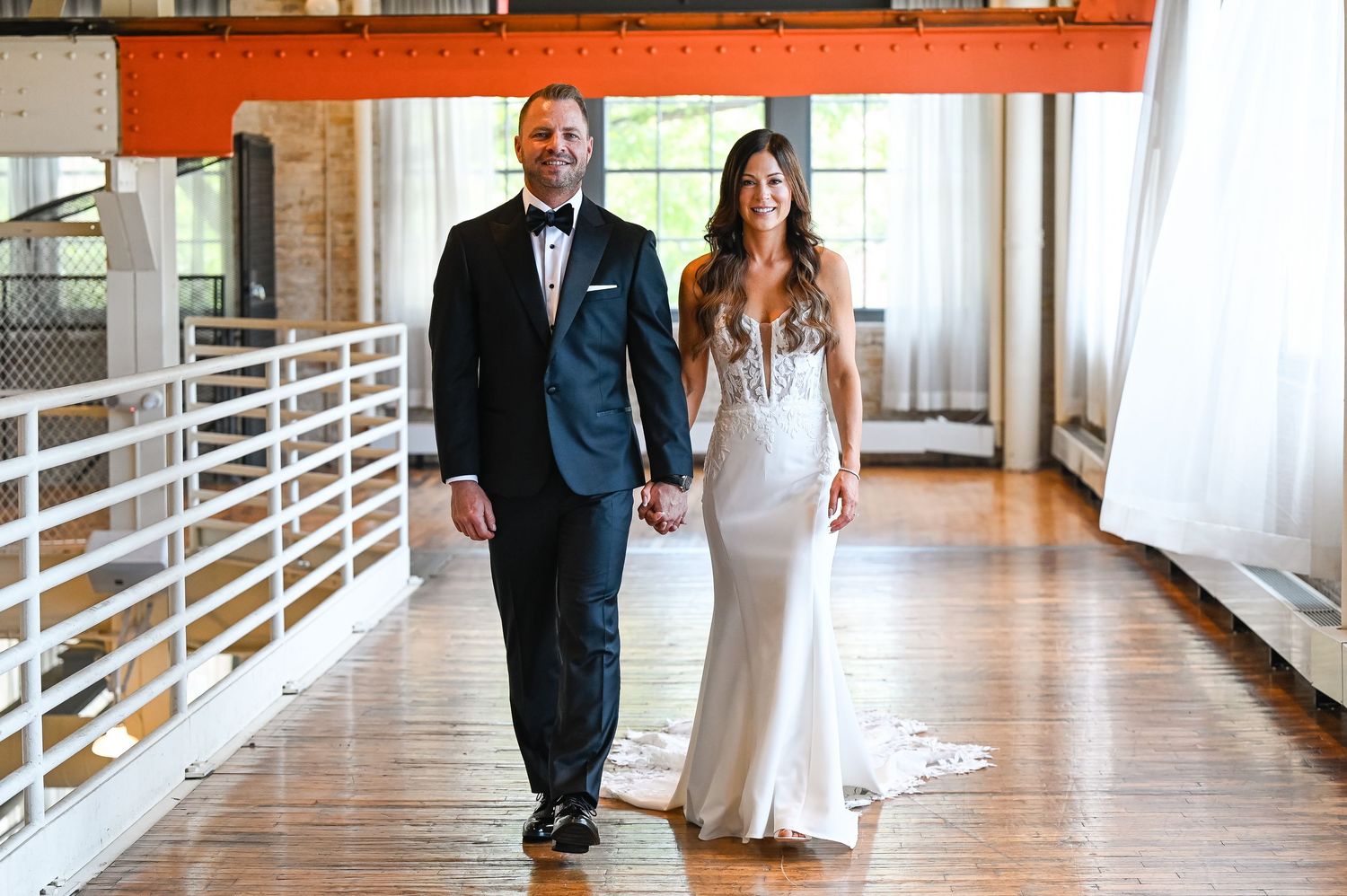 Couple walking together through a bright modern hallway during their wedding.