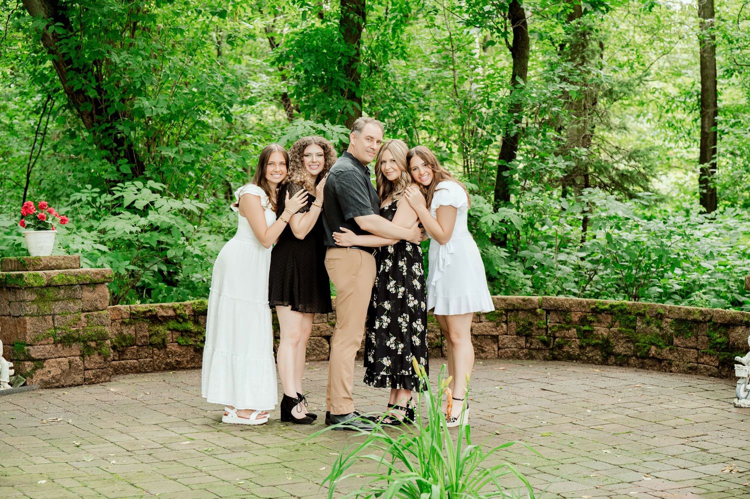 Group poses together for cheerful photo on stone patio in forest setting.