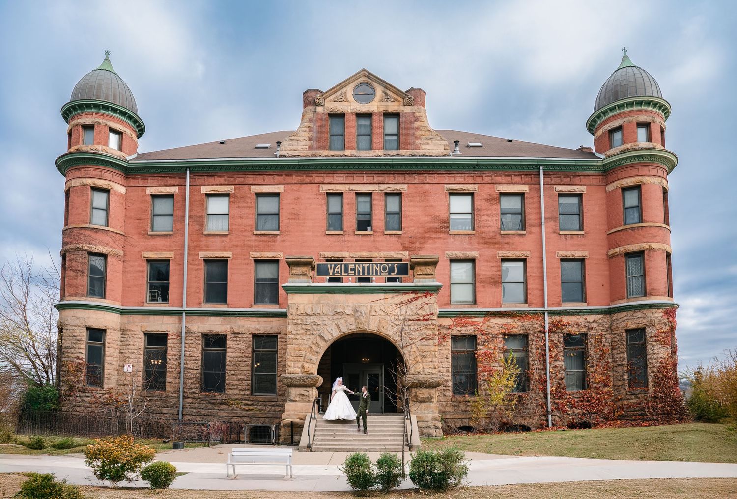 Wedding at The Historic Concord Exchange Minneapolis MN.  red brick building with turrets and a couple in wedding attire on the steps.