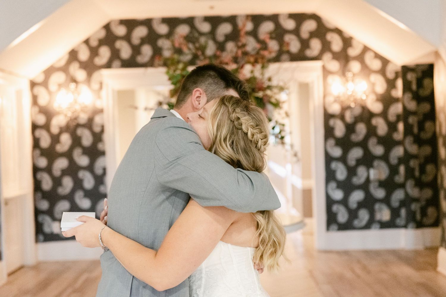 Central MN Wedding Photos | Bride and groom sharing a heartfelt hug during their first look in a decorated wedding venue.