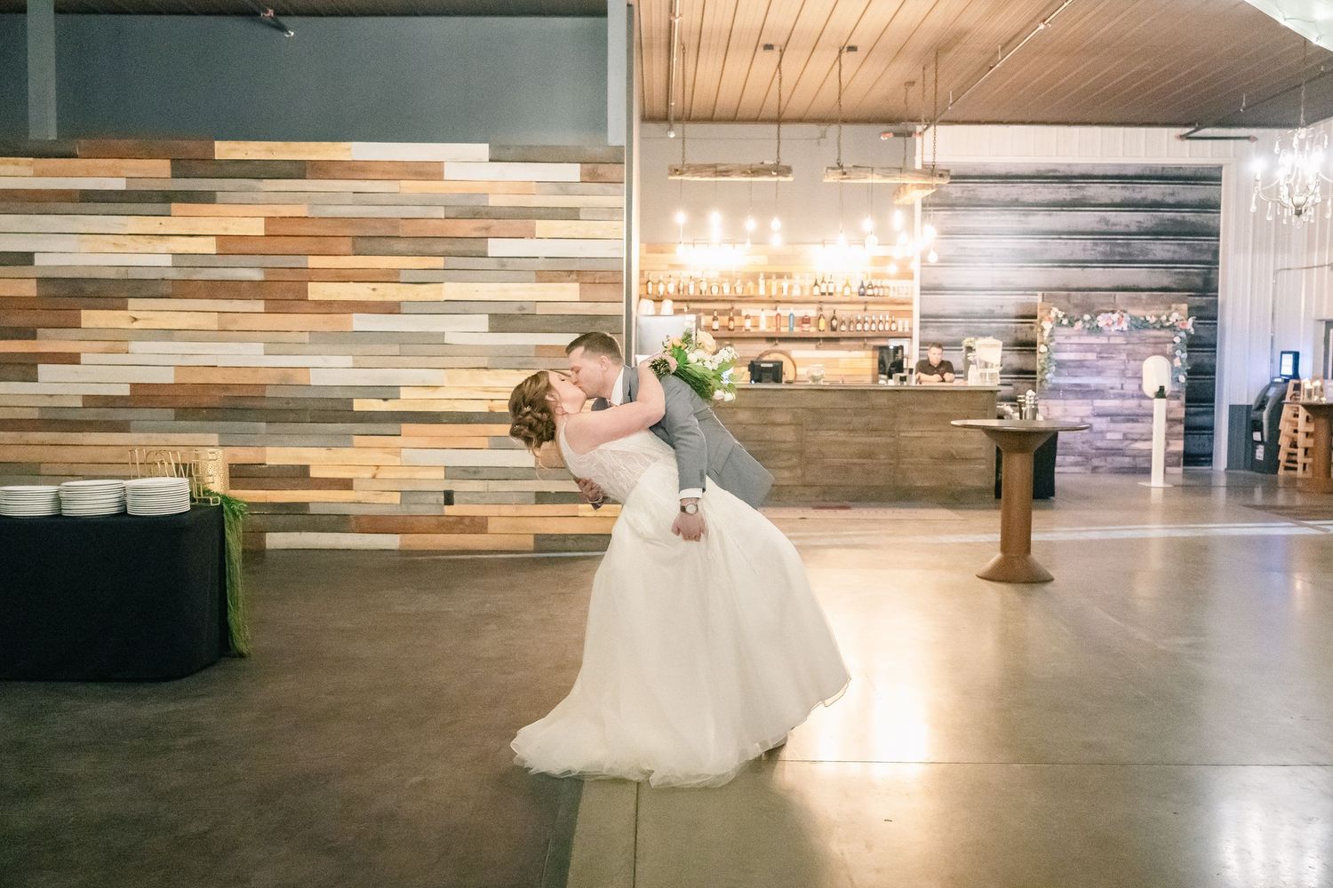 Groom dips bride romantically on dance floor at elegant wedding reception.