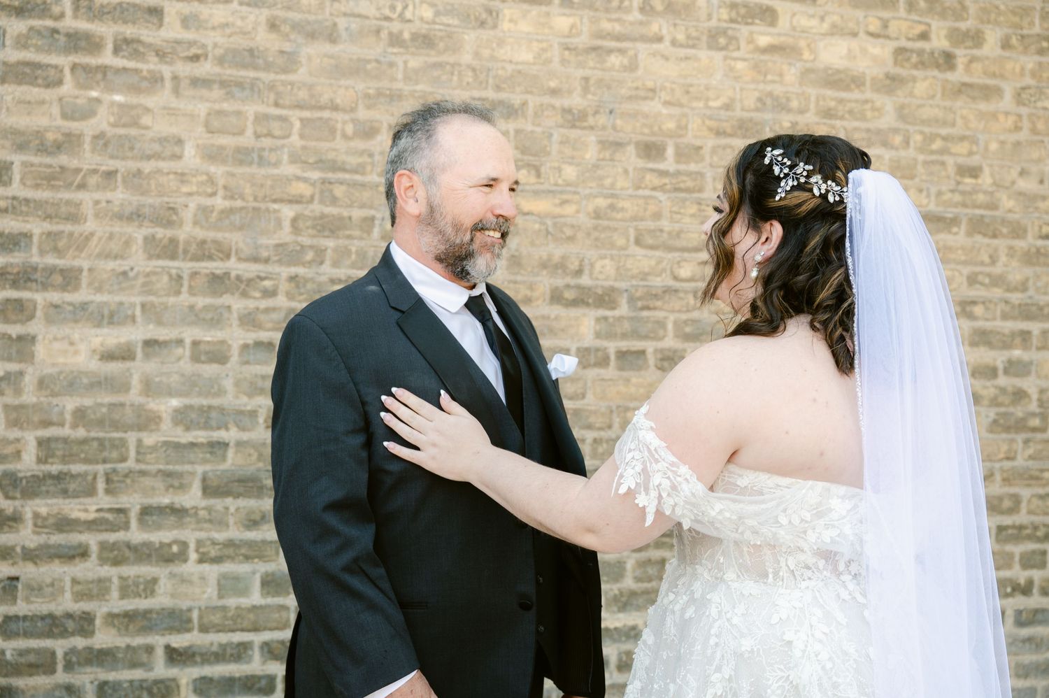 Central MN Wedding Photos - Father seeing bride in wedding dress for first look moment against rustic brick wall.