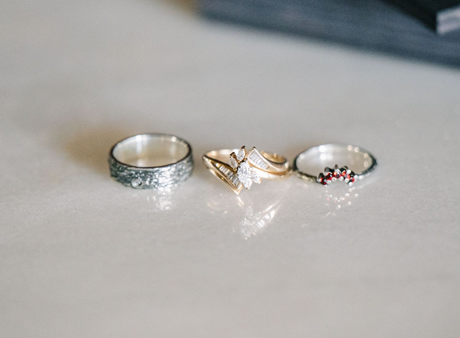 The Historic Concord Exchange wedding rings displayed on a white surface, including a band, gold engagement ring, and ruby cluster ring.