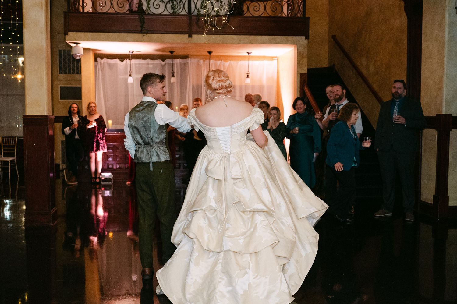 Central MN Wedding Photos | Bride in layered ivory ball gown enters reception hall with groom to applause.