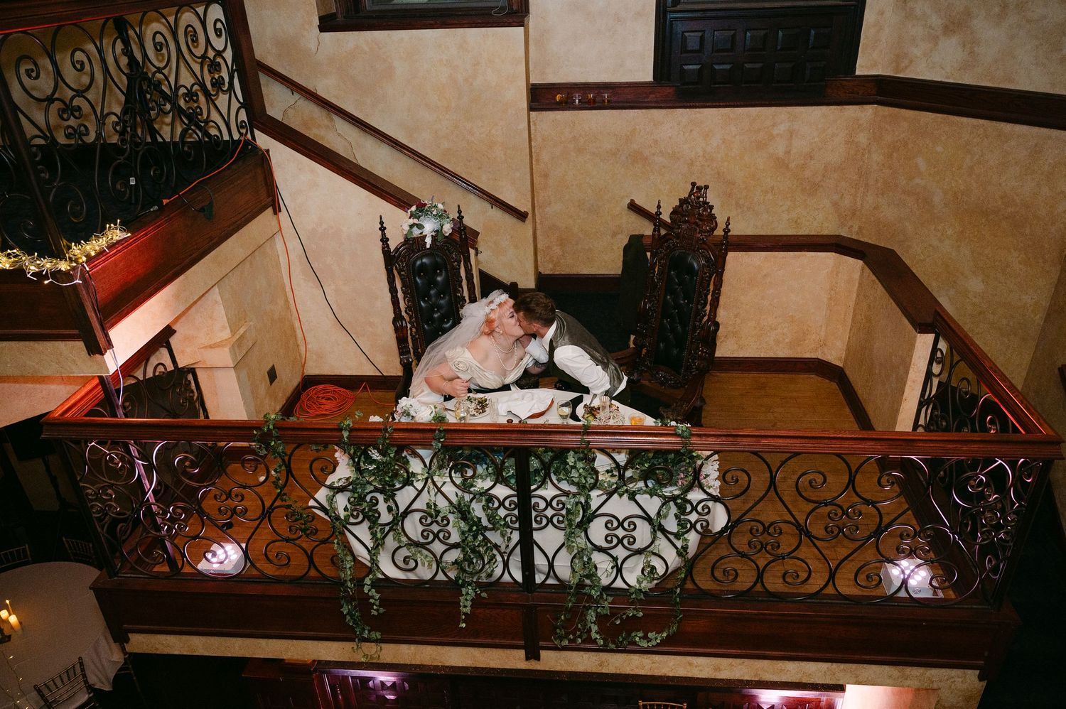 Central MN Wedding Photos | Bride and groom share romantic kiss on ornate balcony with iron railings.