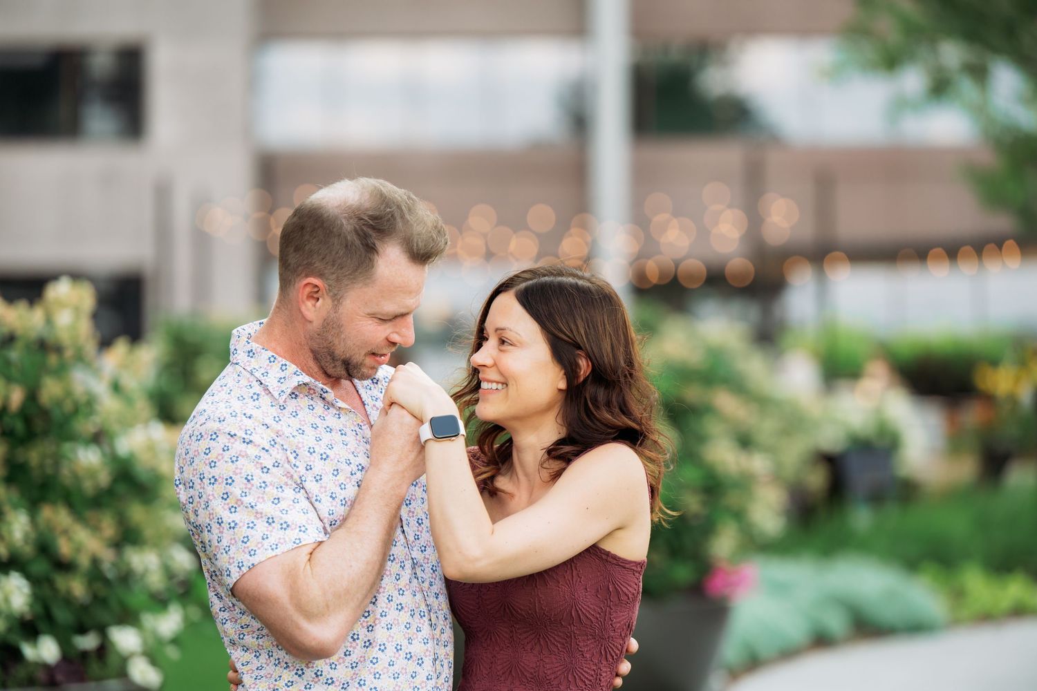 A couple shares a romantic moment together in a lush garden setting with green foliage in the background.