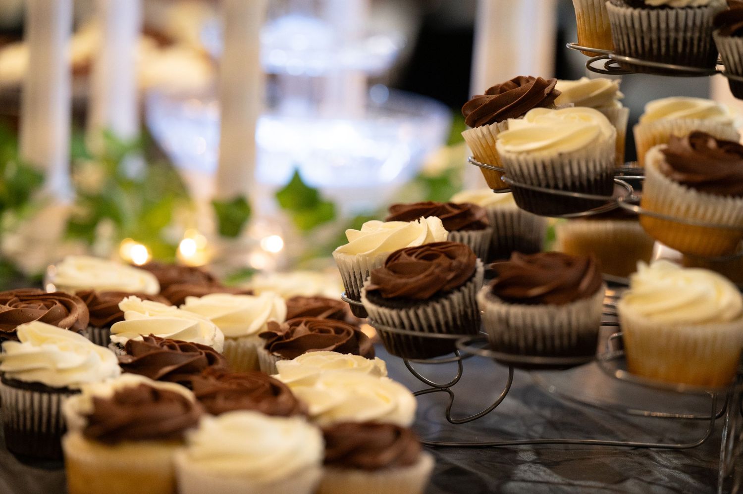Rows of chocolate and vanilla cupcakes with swirled frosting arranged for a wedding dessert table.