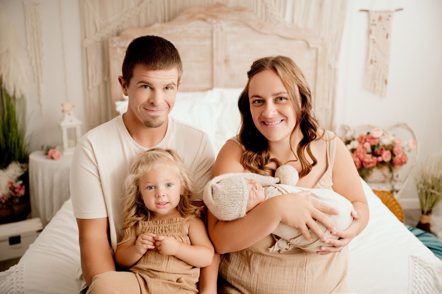 Family portrait on bed with neutral color scheme and floral decor.