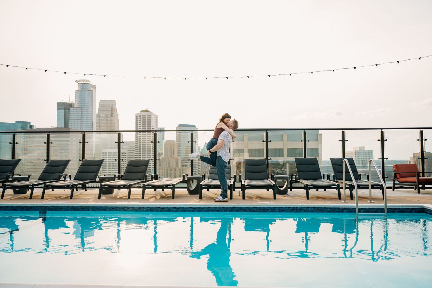 Modern rooftop pool area with city views and string lights creating an urban oasis atmosphere.