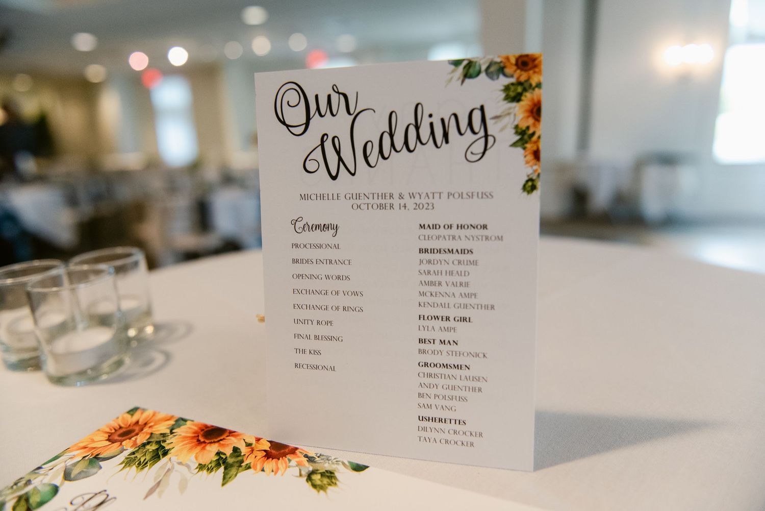 Central MN Wedding Photos | Elegant sunflower-themed wedding program displayed on a table at an autumn wedding reception.