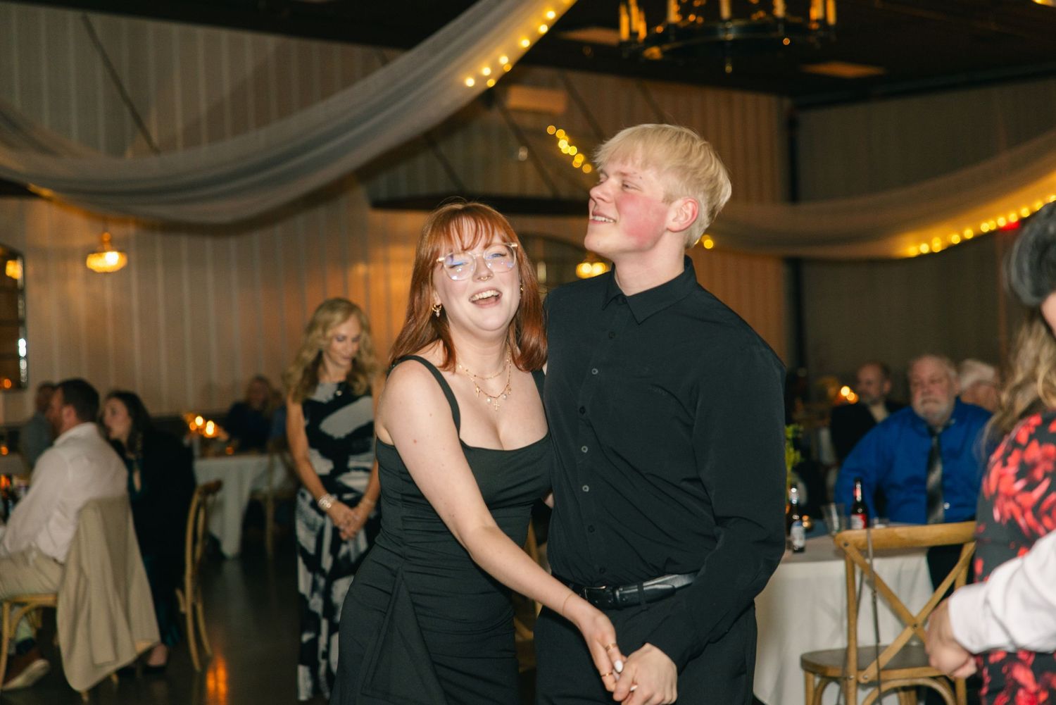 Young couple smiling and dancing together at an elegant wedding reception celebration.