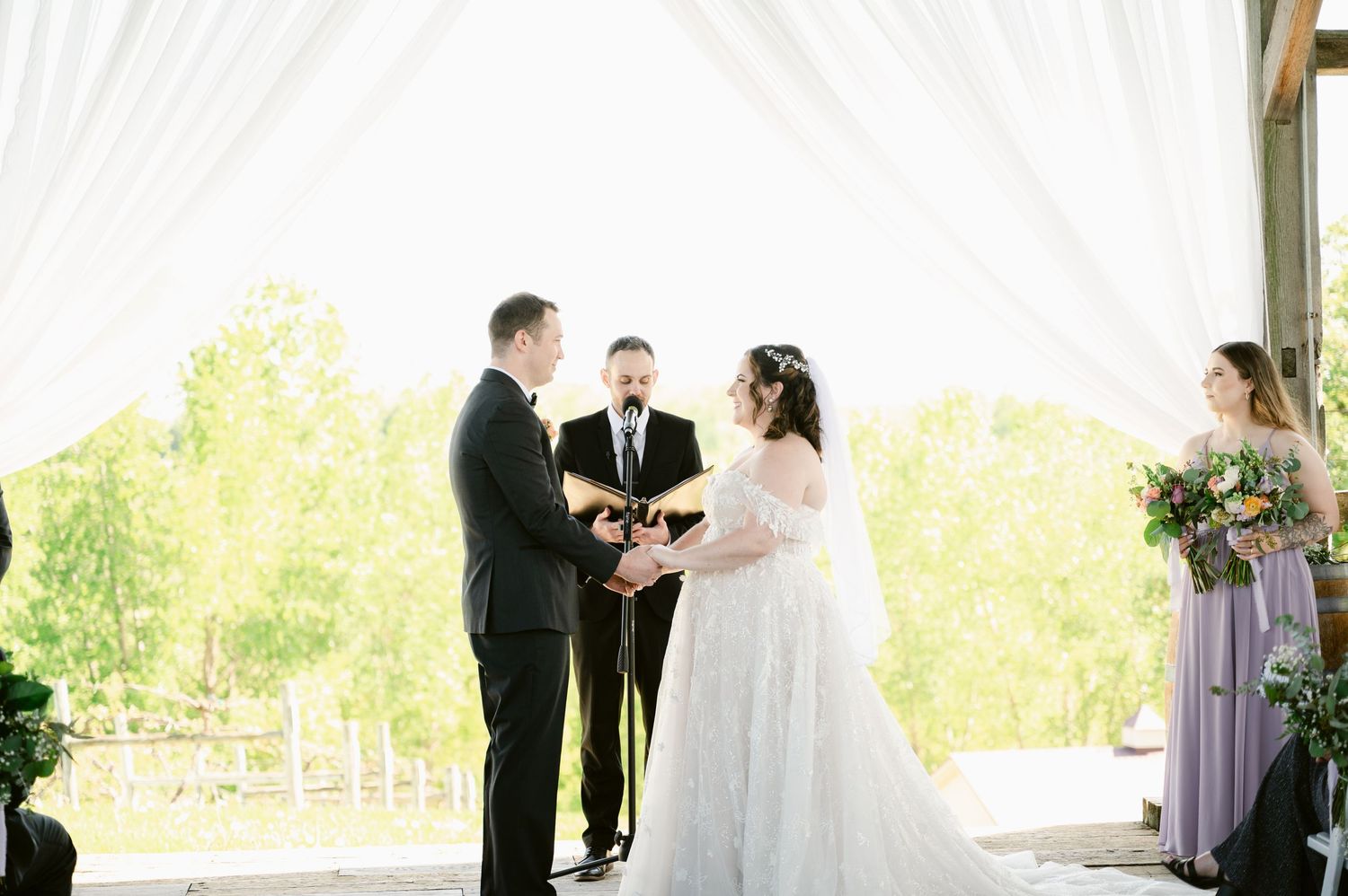 Central MN Wedding Photos - Bride and groom exchanging vows at outdoor wedding ceremony with white draping.