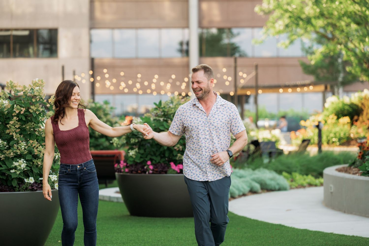 Couple sharing a romantic dance moment on a terrace with decorative planters and twinkling lights.