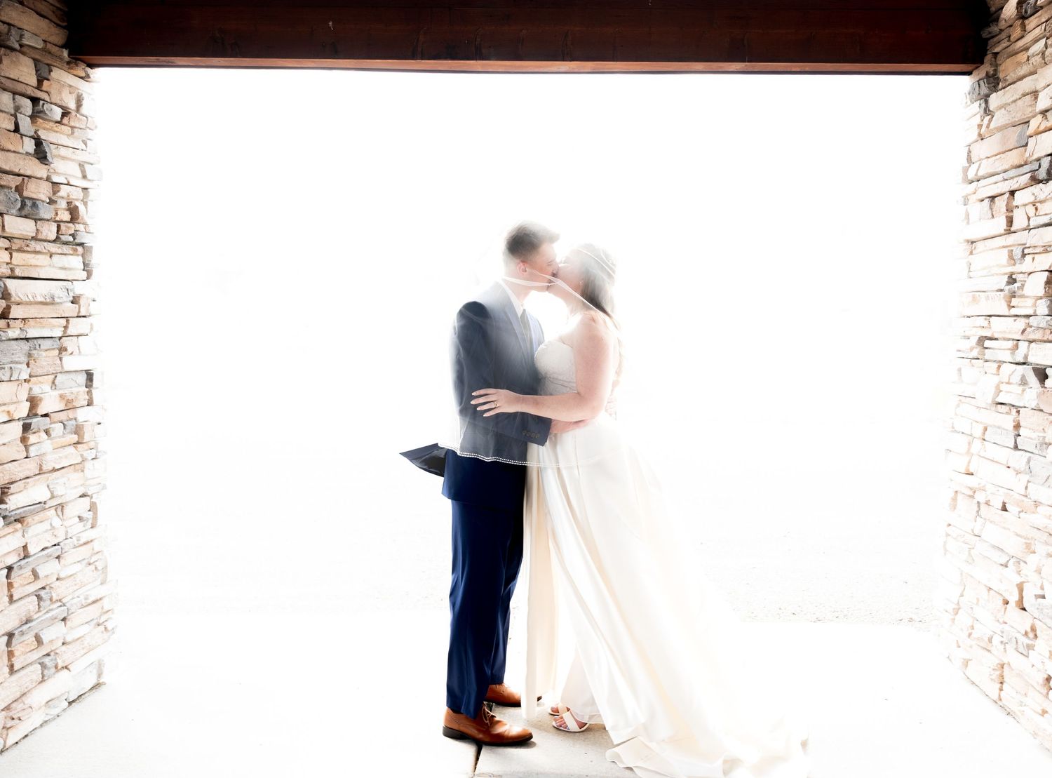 A couple shares a romantic dance in a rustic stone hallway with arched columns and soft lighting. Pease Minnesota Wedding at Northern Lights