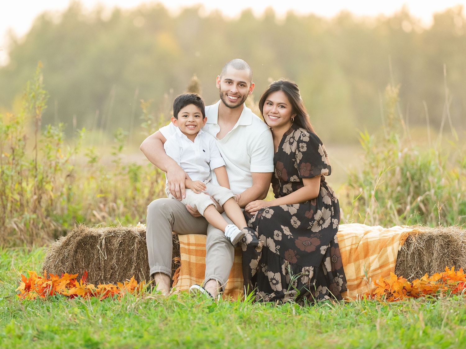 Family relaxes together in a golden field during sunset with orange wildflowers blooming in the background.