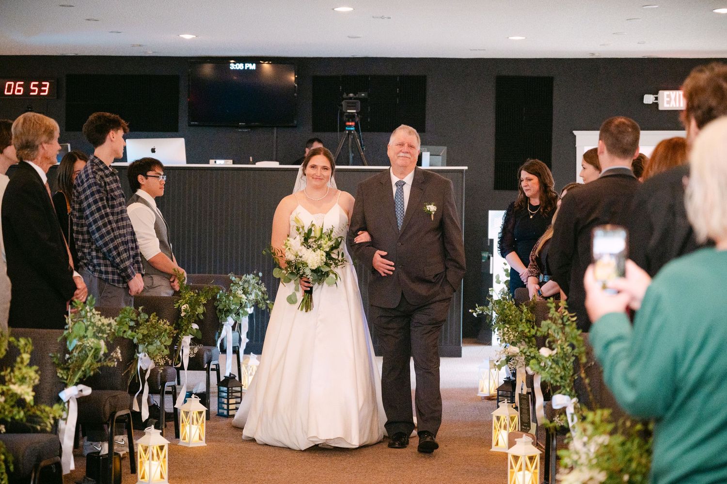 Panoramic view of wedding ceremony setup with white chairs and floral aisle decorations.