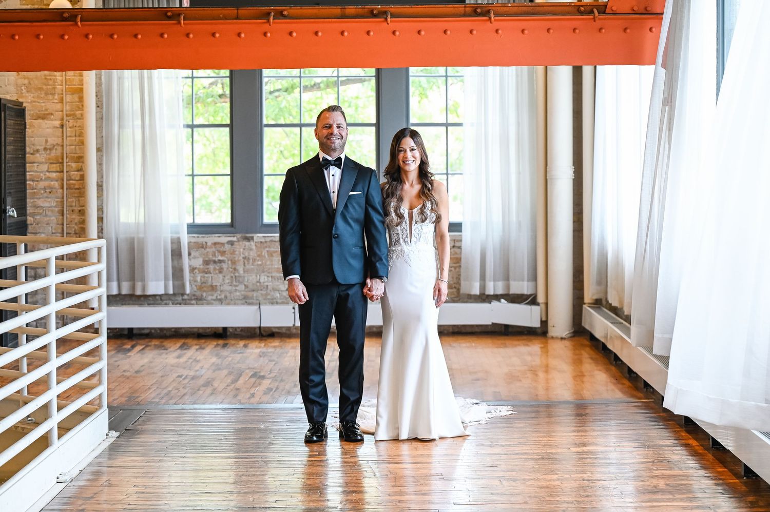 Couple sharing an emotional first look in a sunlit industrial venue.