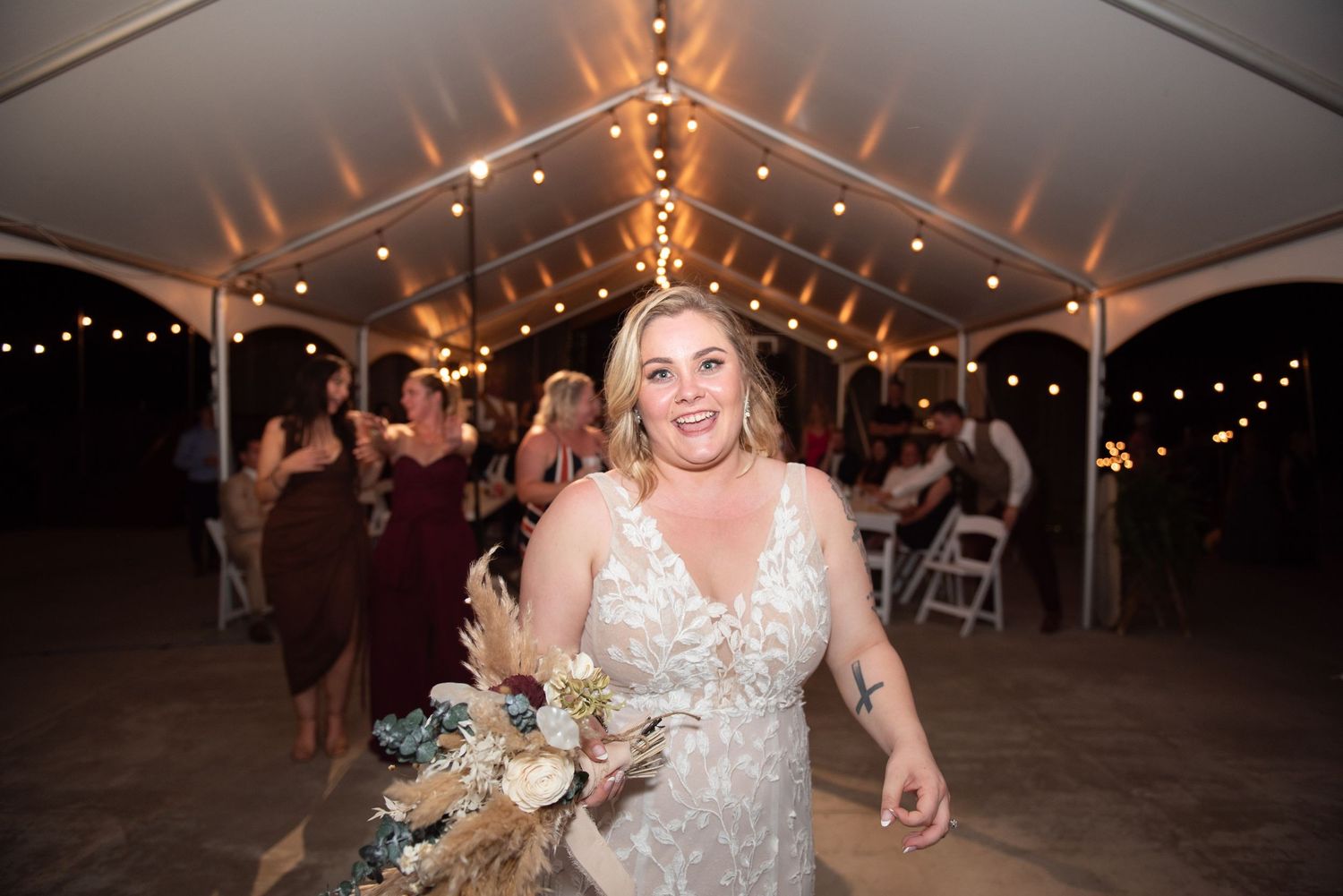Wedding reception tent illuminated with string lights creating magical atmosphere.