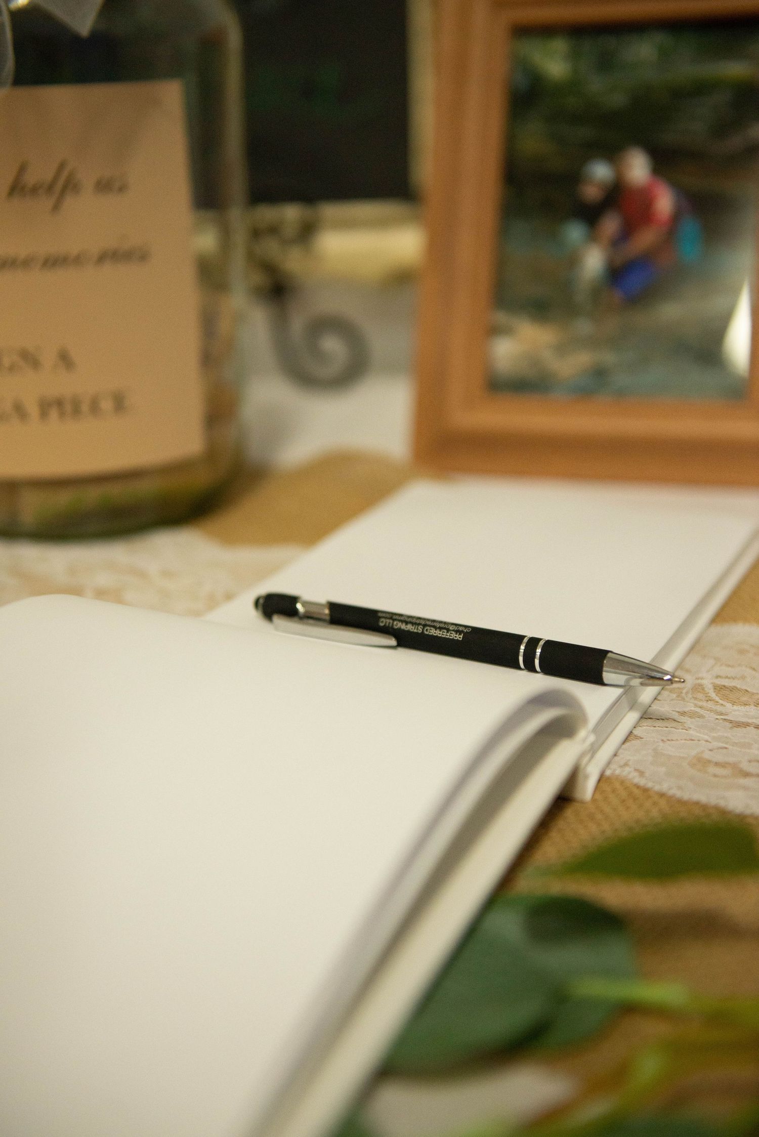 Open guest book with black pen on lace tablecloth at wedding reception. Zimmerman MN Weddings