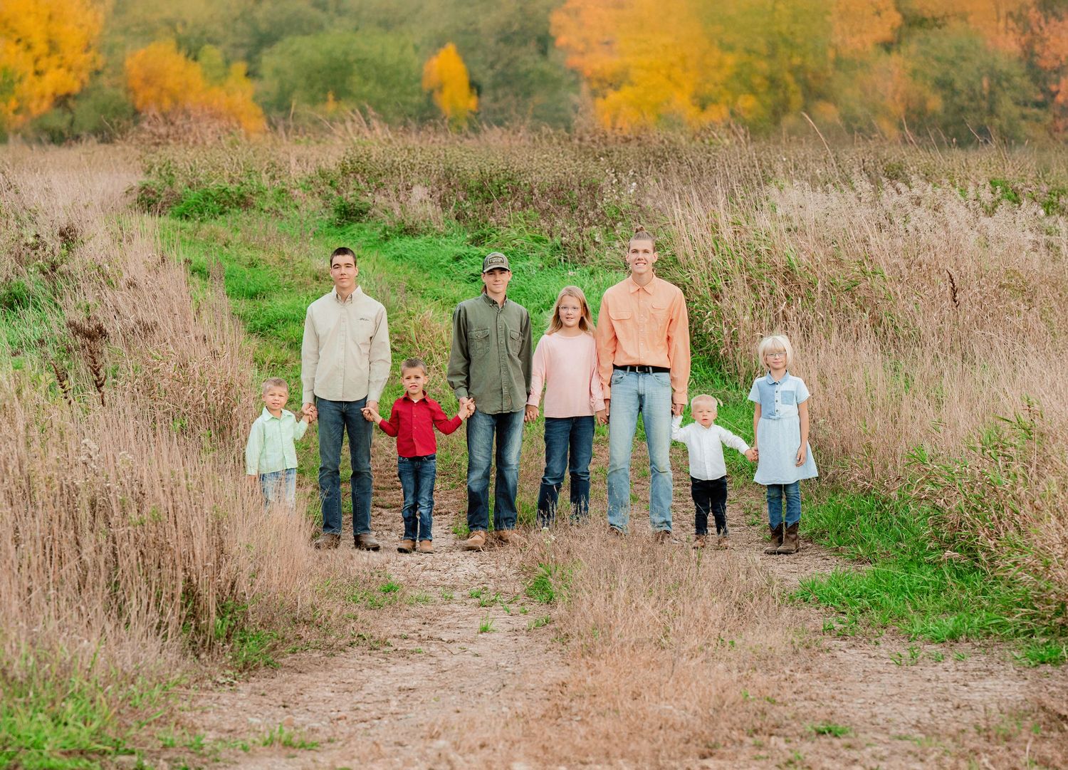 A group poses on a nature trail surrounded by autumn foliage and tall grass.