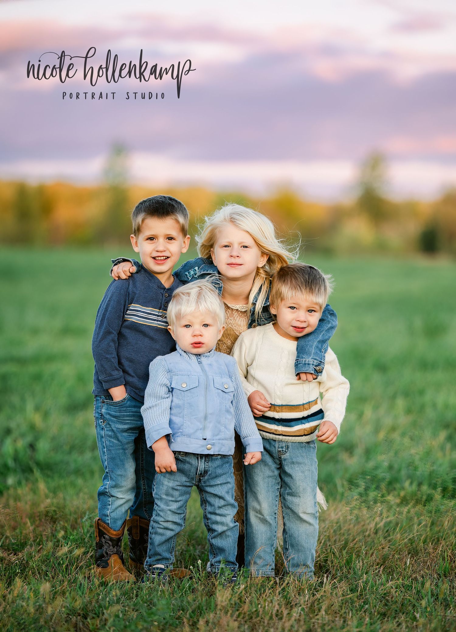 Group of children in casual wear standing together in outdoor field during sunset.