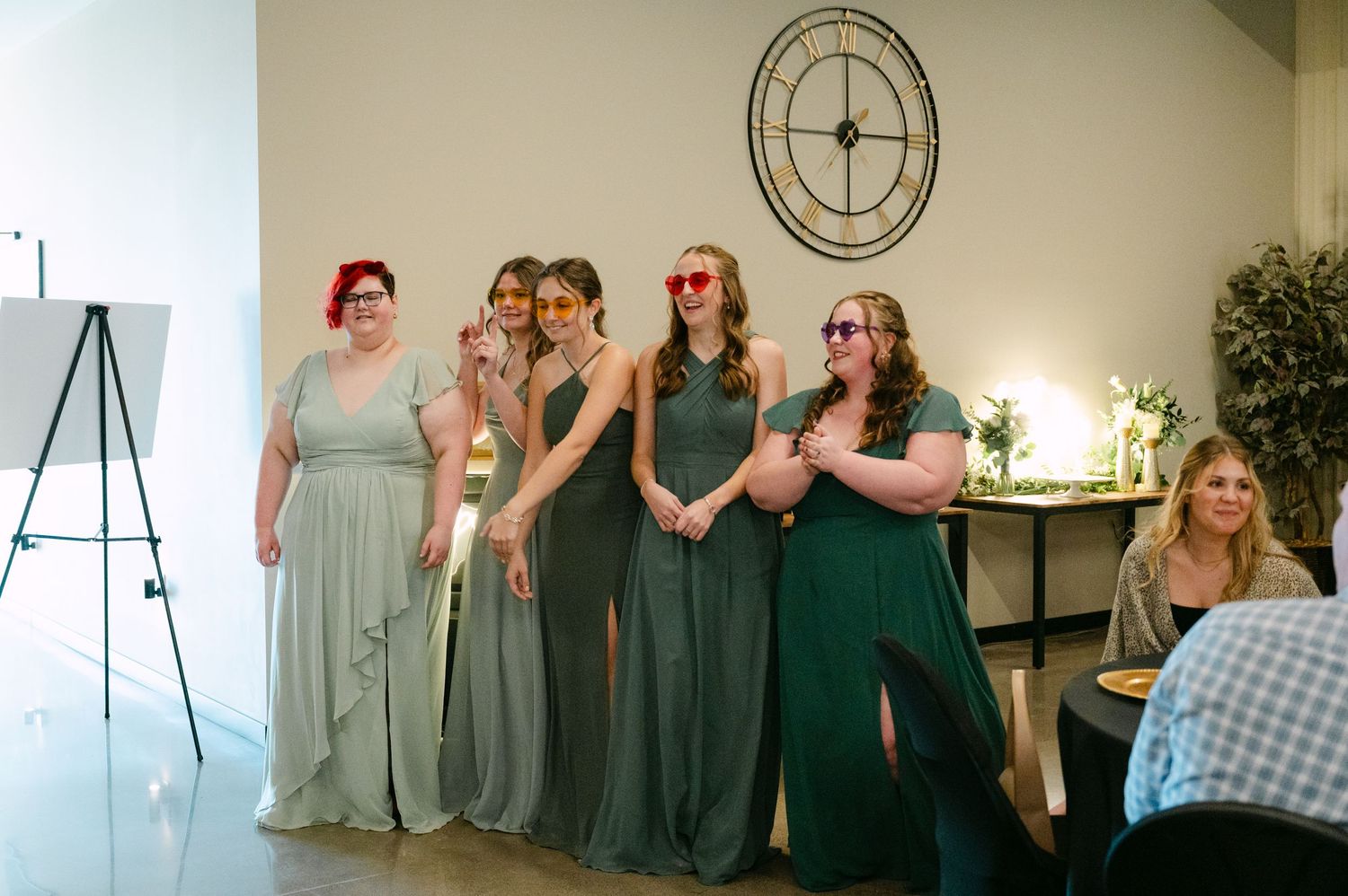 Wedding party members in light blue and dark green bridesmaid dresses pose together during a photo session.