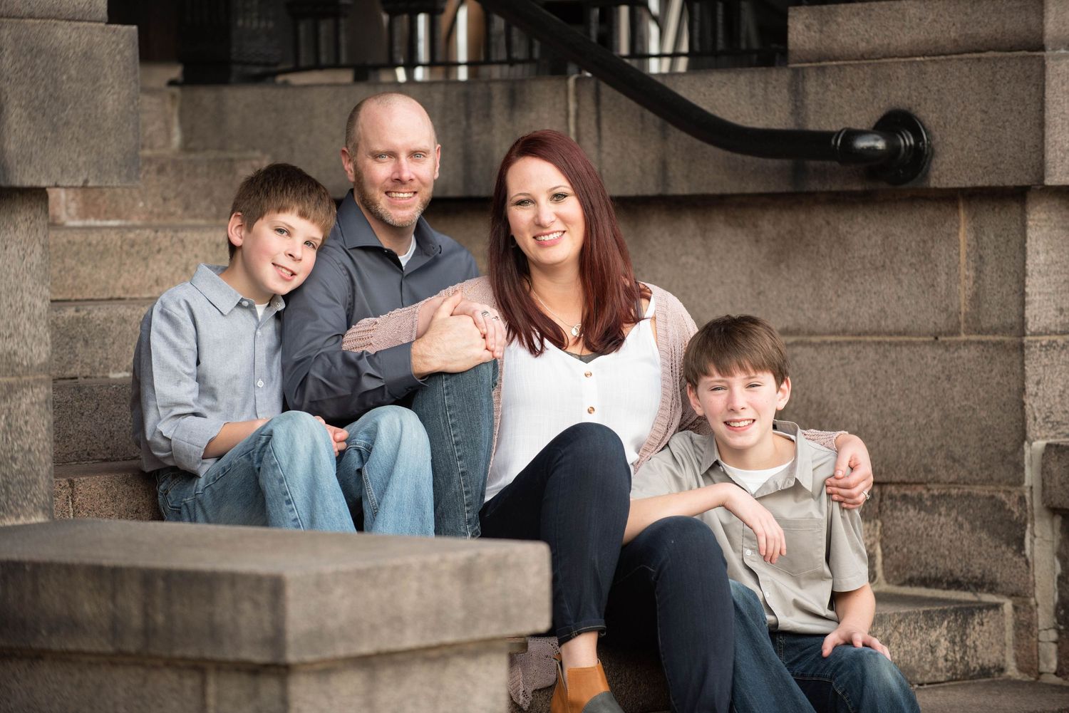 A group sits together on stone steps during an outdoor family photo session at dusk.