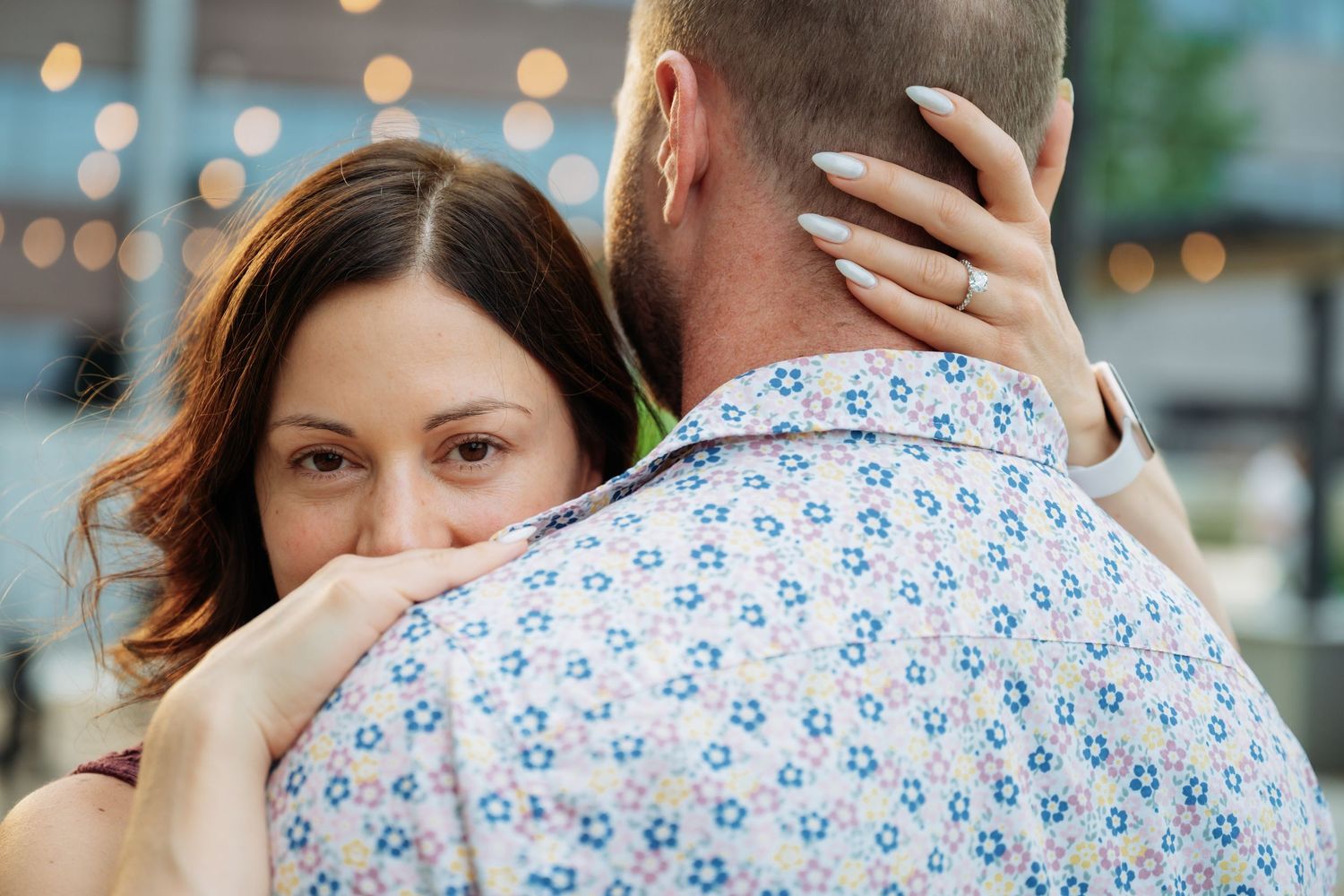 A close-up shot of a couple sharing an intimate moment outdoors with soft bokeh lighting effects.