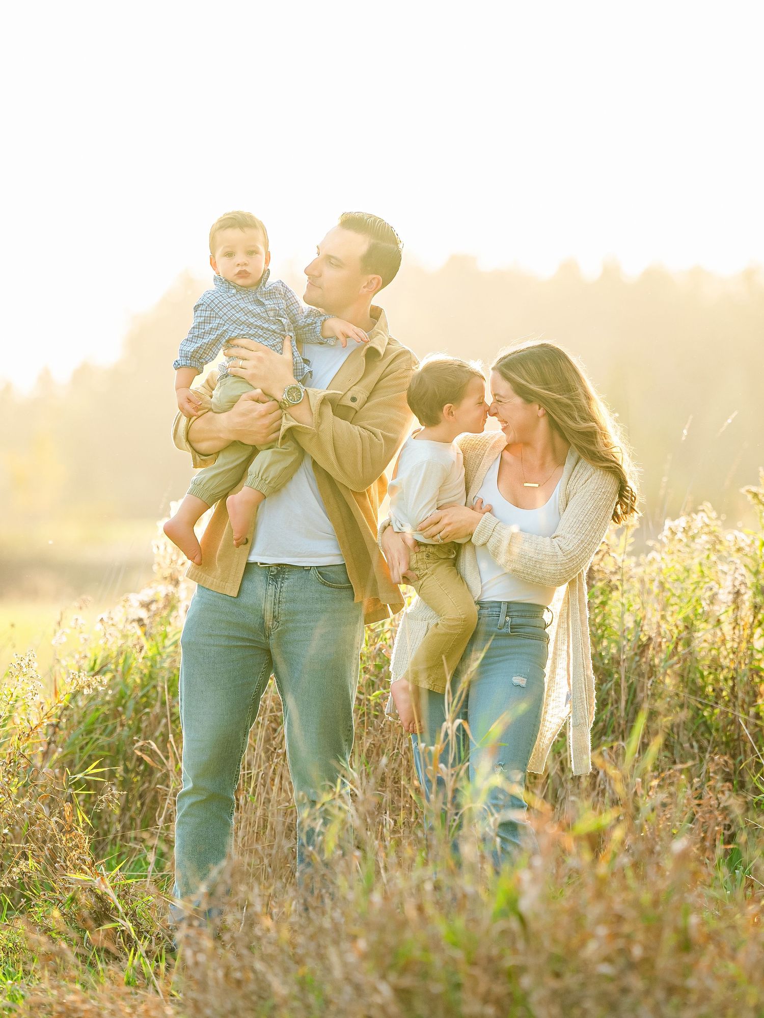 In central Minnesota a Family enjoying a playful moment together in a sunlit meadow with wildflowers during golden hour.