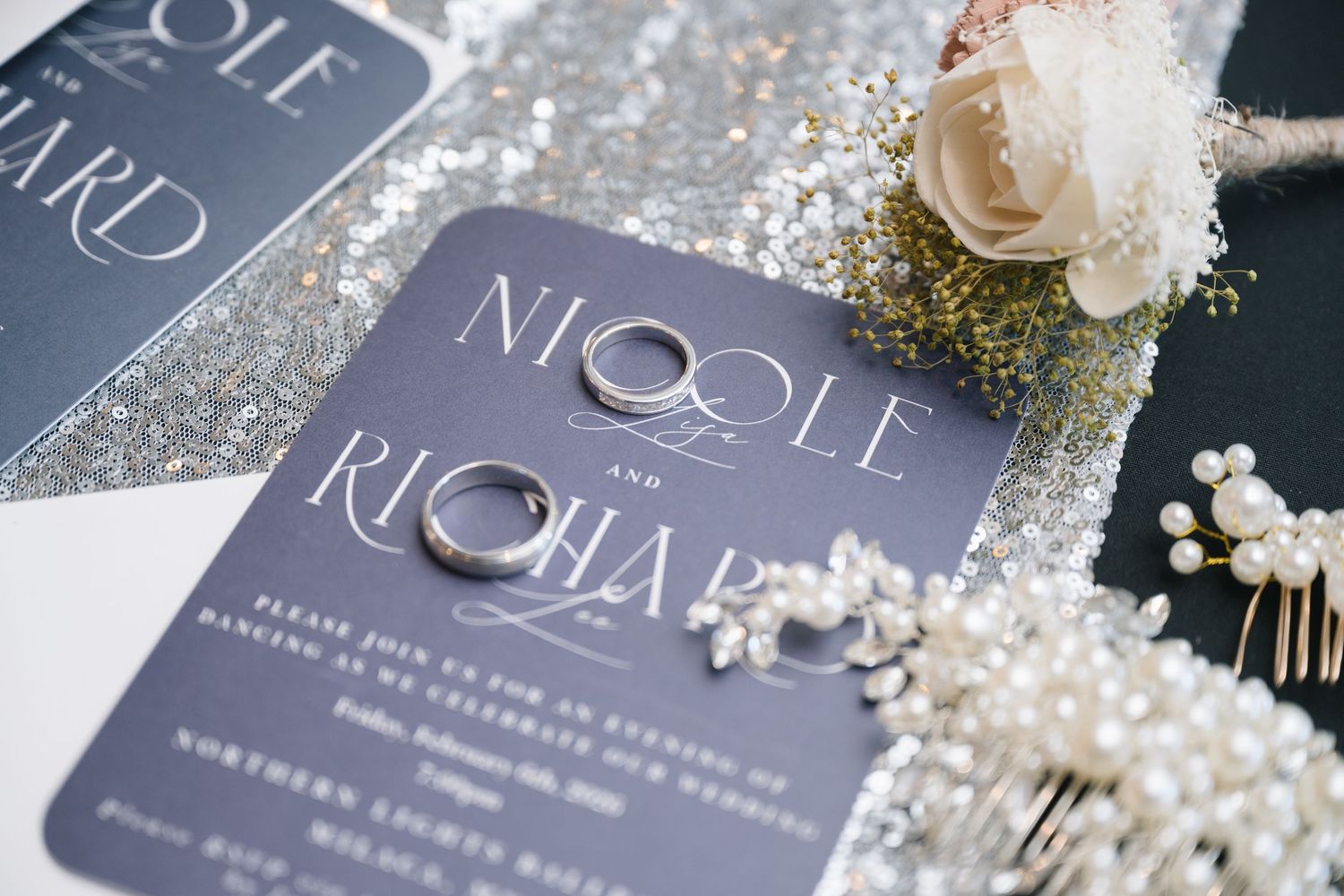 Elegant gray wedding invitation cards with metallic details and floral accents displayed on a light surface.