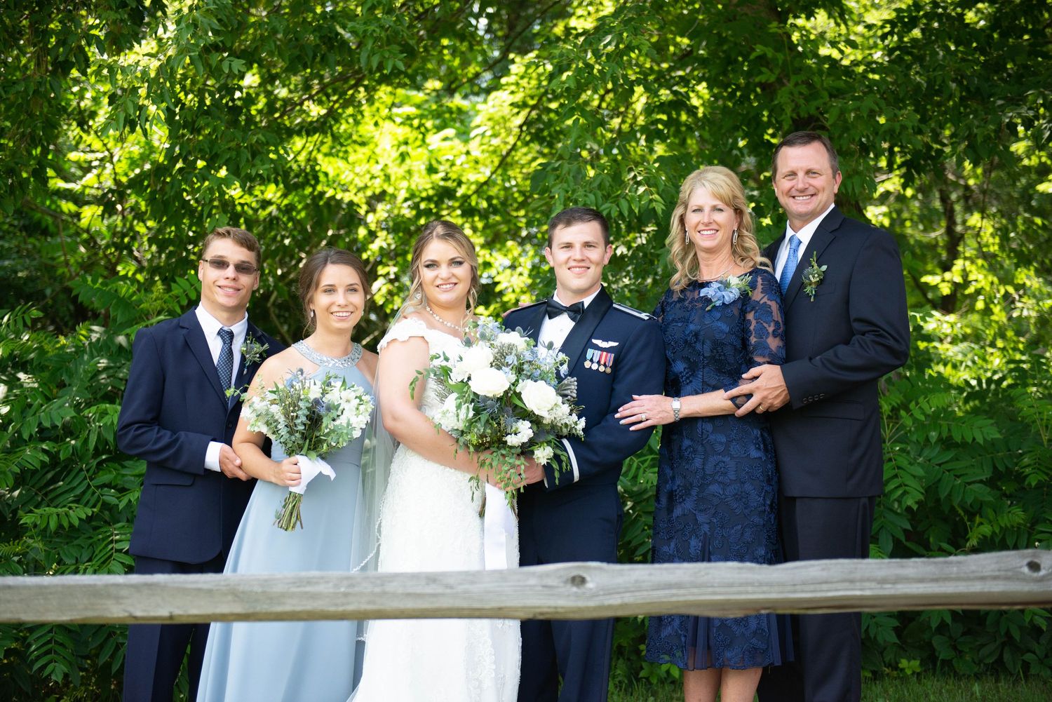 Wedding party members stand together laughing in a wooded outdoor setting. Zimmerman MN Weddings