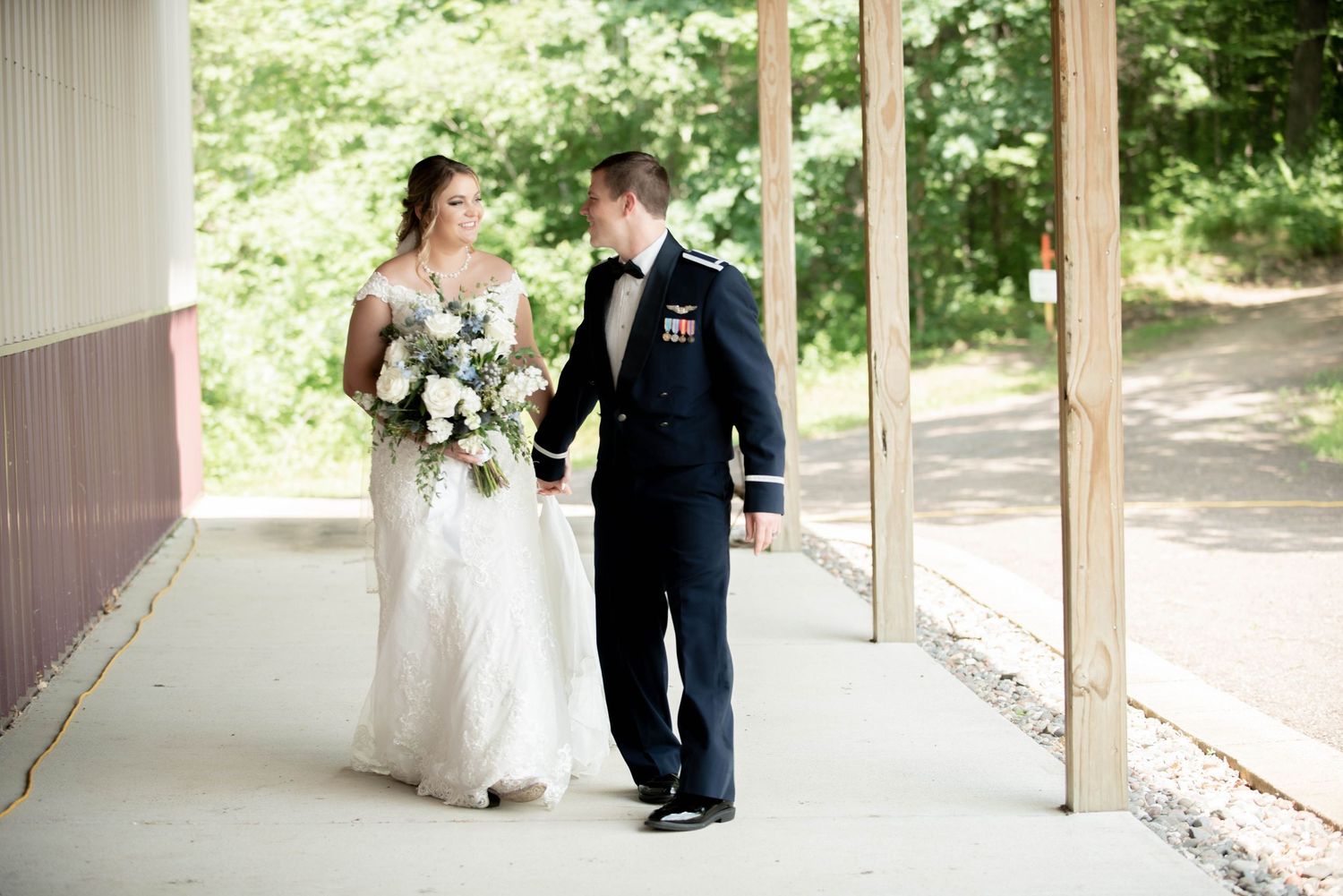 A couple in wedding attire walks together under a covered walkway. Zimmerman MN Weddings