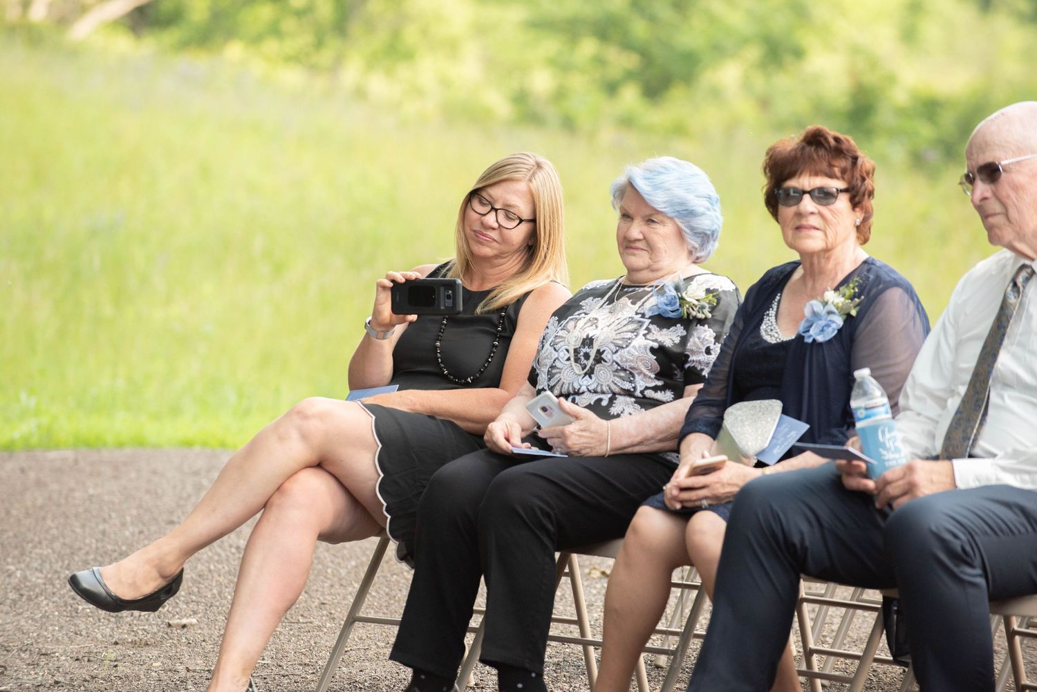A group of people sitting in chairs outdoors having a casual gathering on a sunny day. Zimmerman MN Weddings