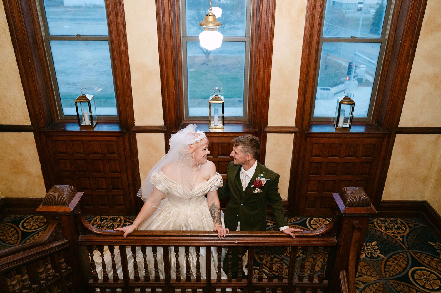 Central MN Wedding Photos | Bride and groom sharing romantic moment on wooden staircase landing in elegant historic venue.